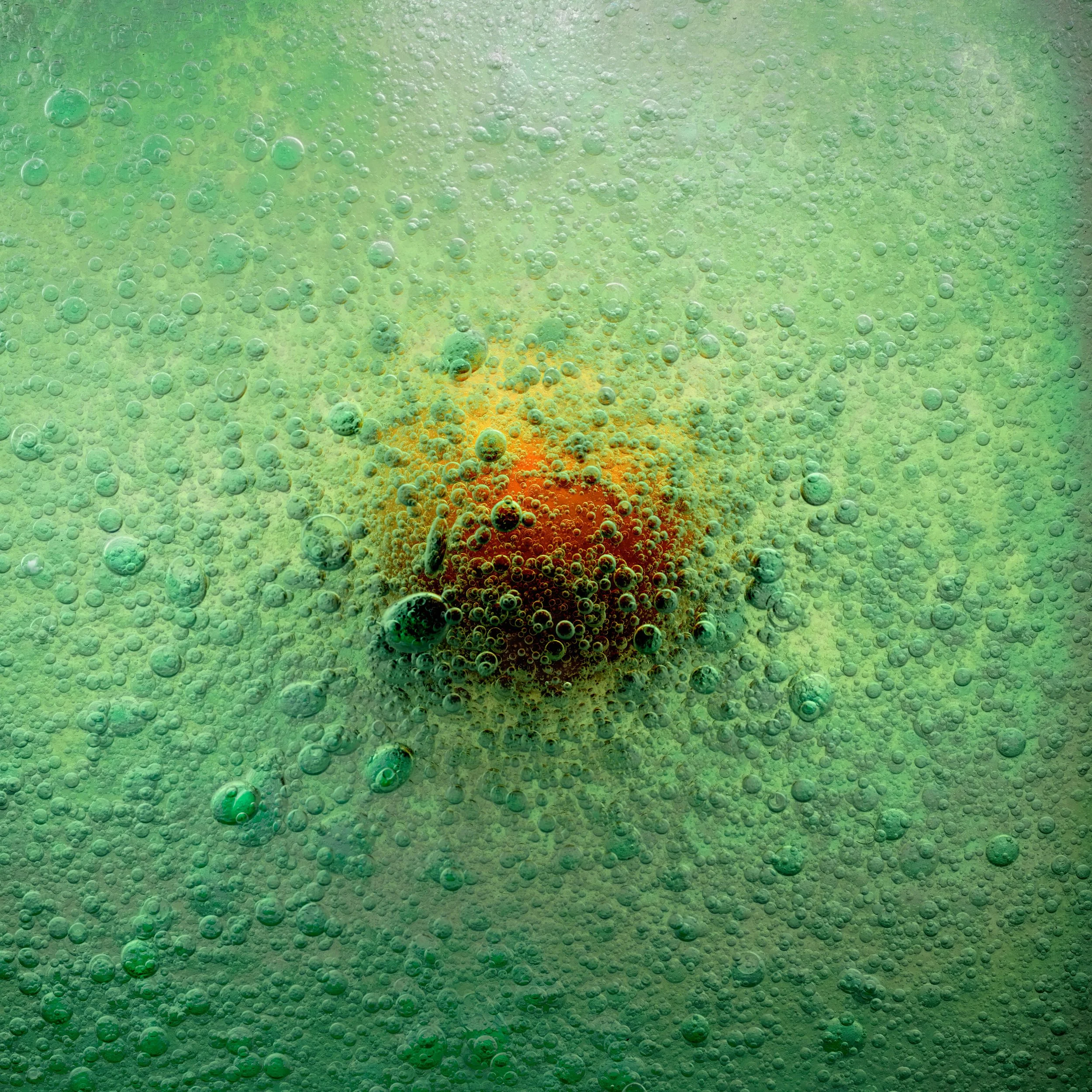 An orange object submerged in a green liquid with many small bubbles surrounding it.