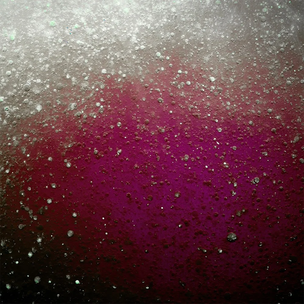 Close-up of bubbles forming on a surface with a gradient background from white to pink.