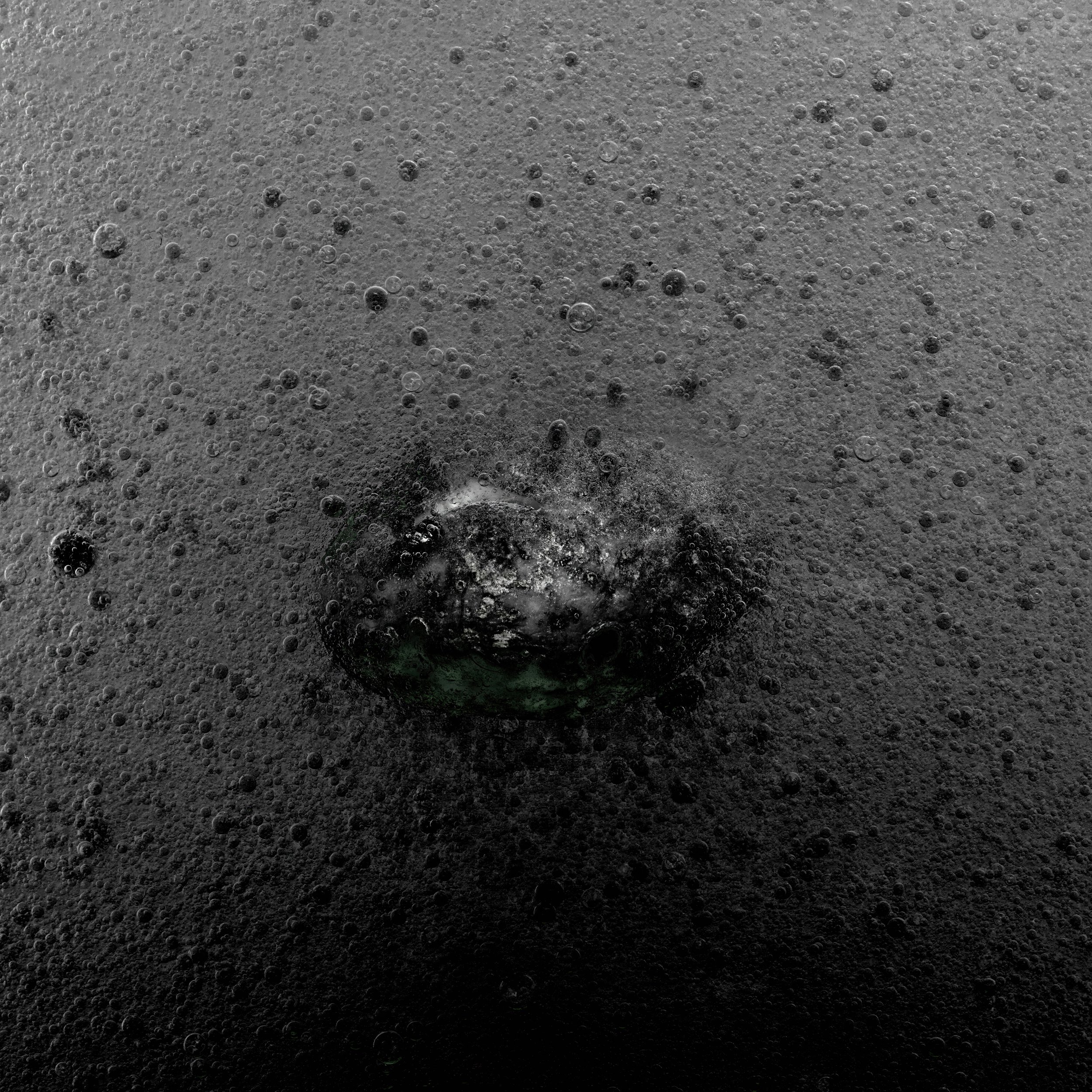 Close-up of a black, bubbled carbonated drink with a partially visible green glass bottle submerged in the foam.