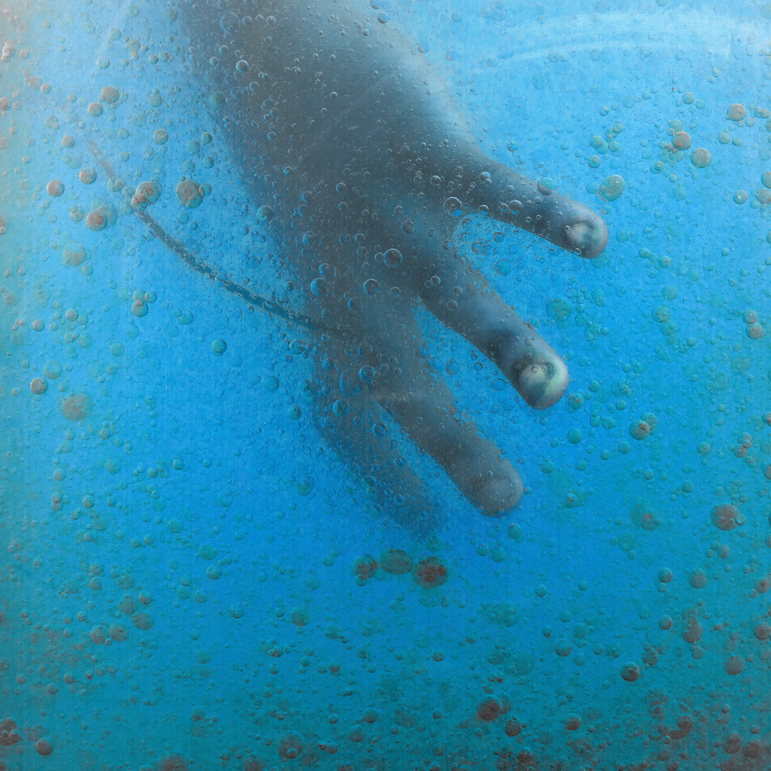 A hand reaching out underwater with bubbles surrounding it.