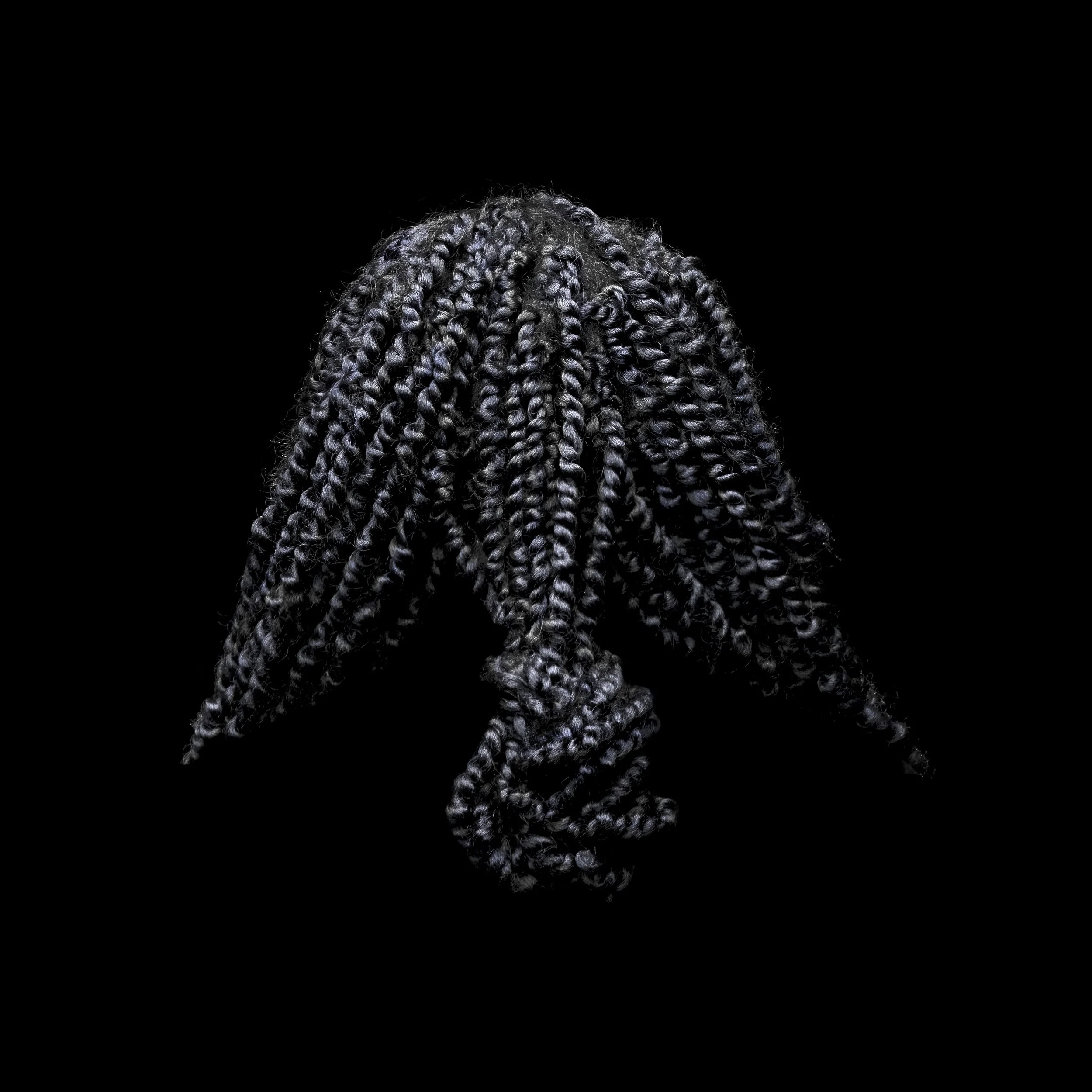 Close-up of braided hair against a black background.