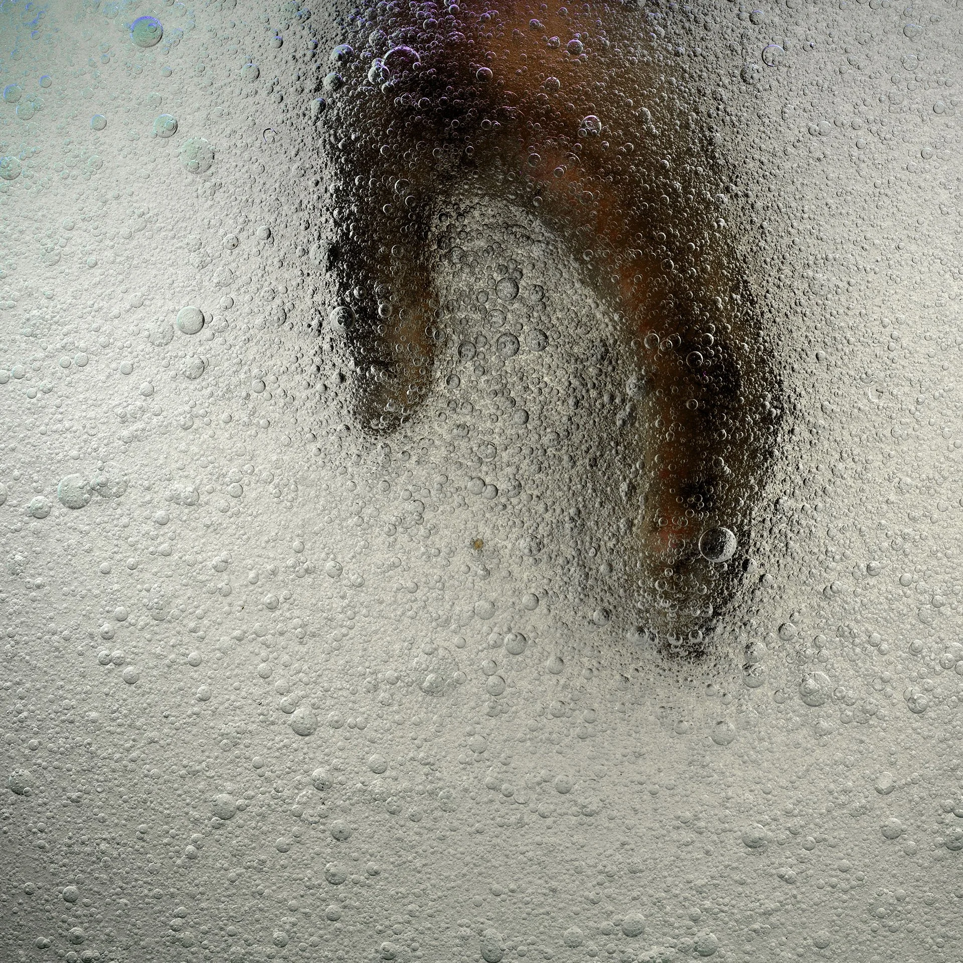 A person is visible through a frosted or textured glass surface, obscured by condensation and bubbles.