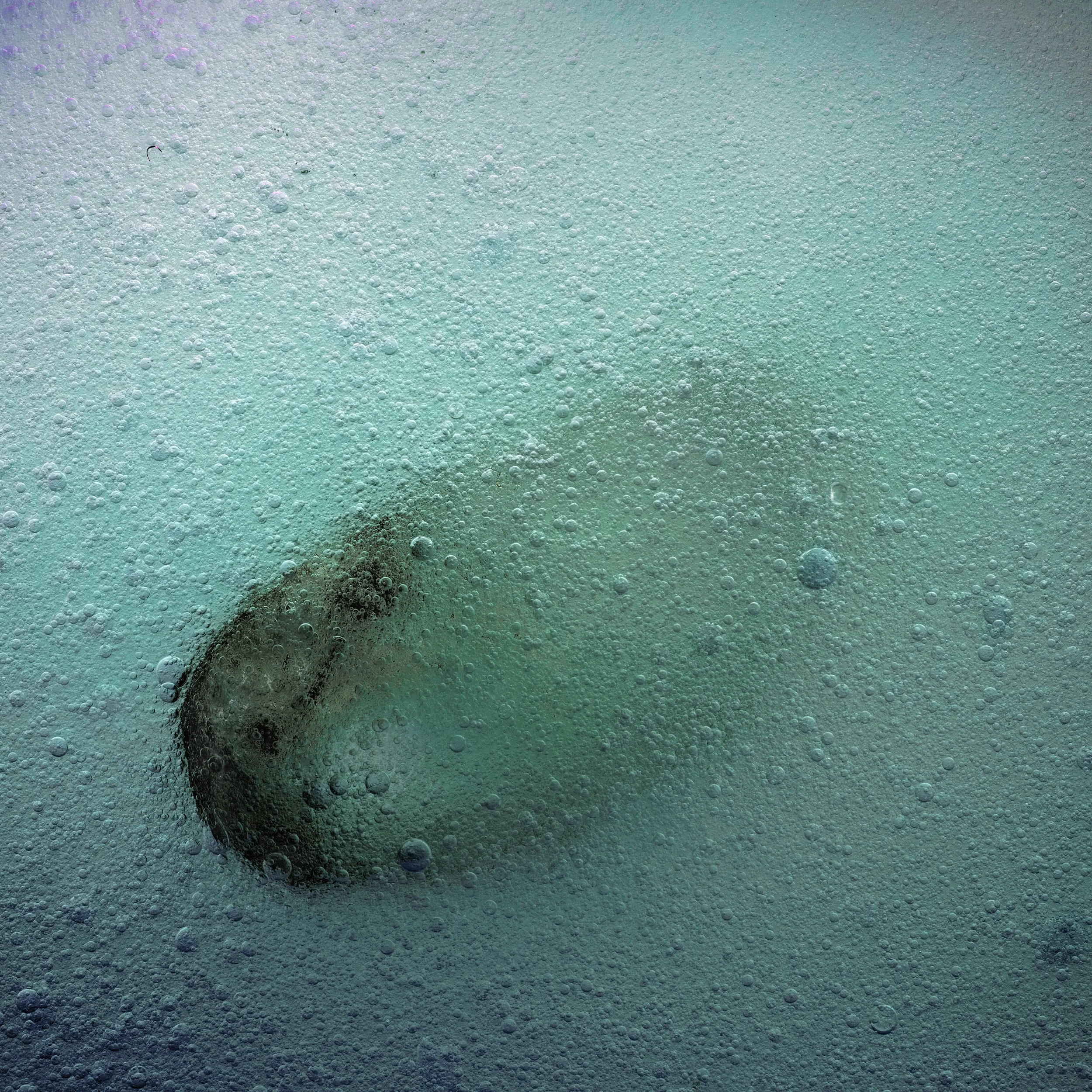 A person jumping into a swimming pool surrounded by bubbles and water.