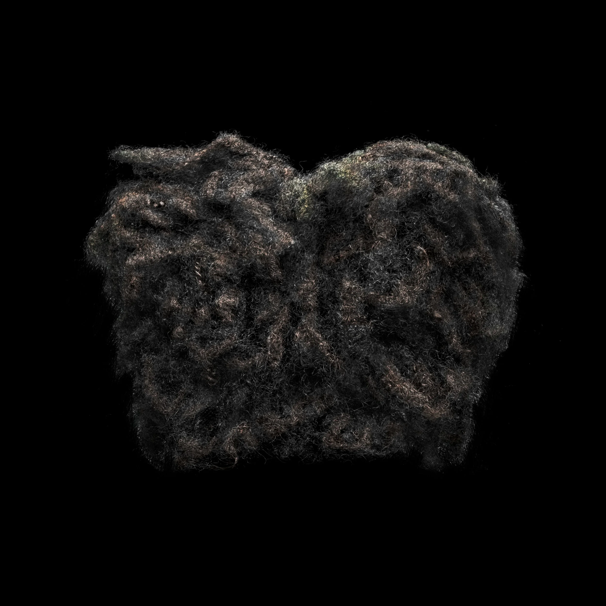 A close-up of a mass of thick, curly, black and brown dreadlocks on a black background.