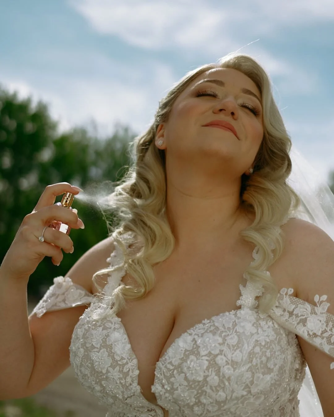 Bride in a lace gown spraying perfume during bridal prep at a Wisconsin wedding, candid wedding photography by Nicole Kilday