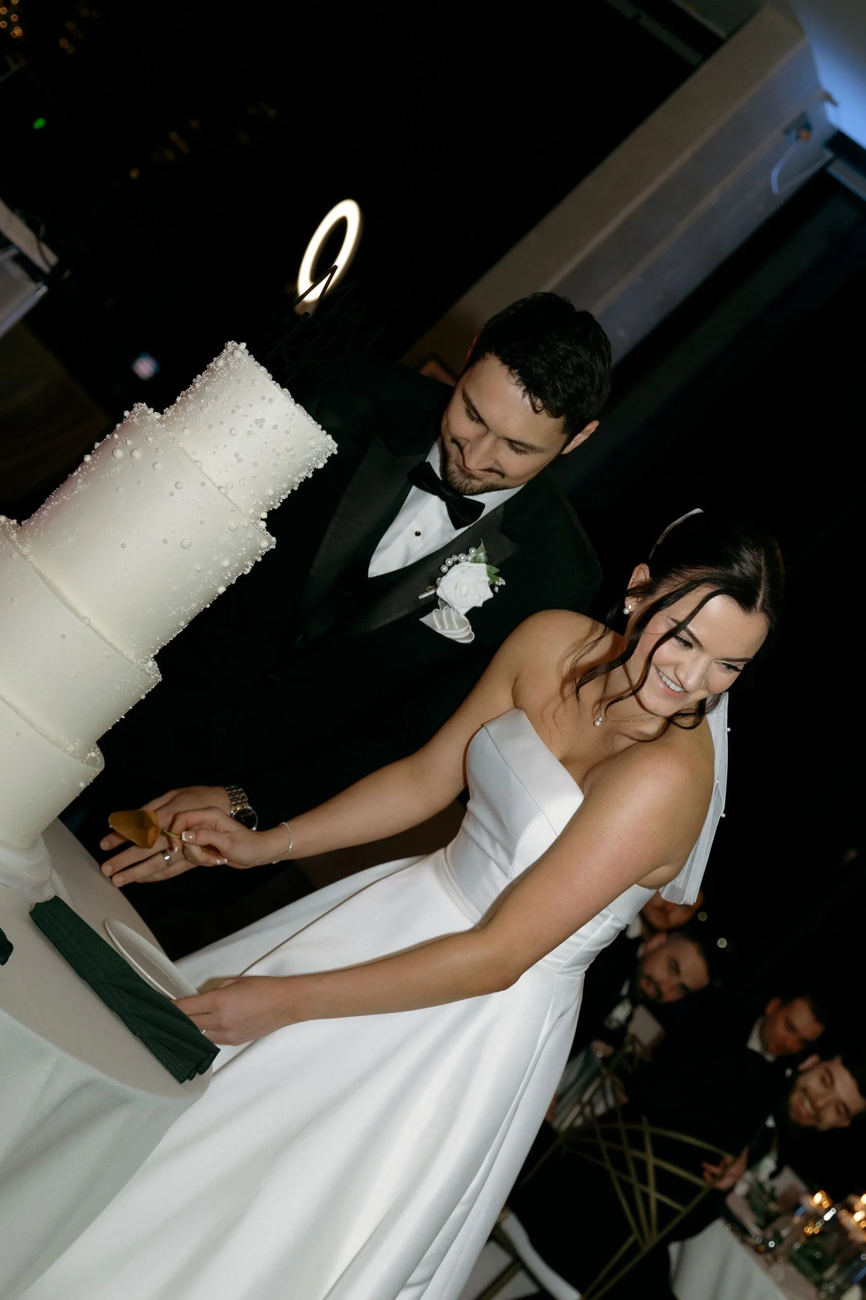 Bride laughing while her and her groom cut their cake during their wedding reception at Sky On Nine in Chicago, IL