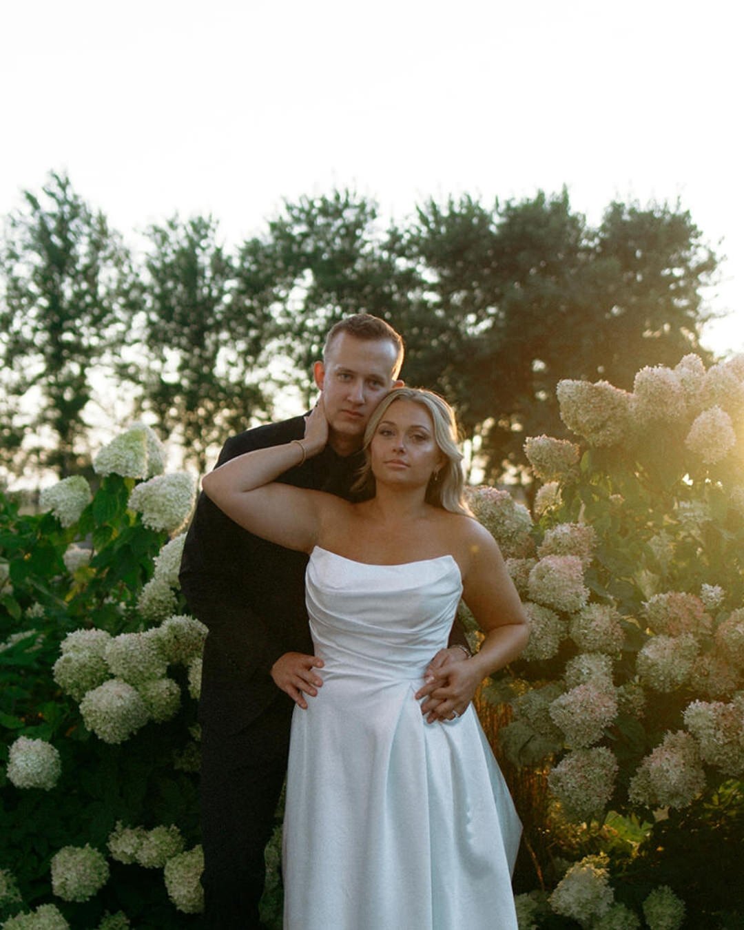 Bride and groom posed among white hydrangeas in golden hour backlight — Illinois and Wisconsin wedding photographer Nicole Kilday at Bluestem Farm and Events, Illinois