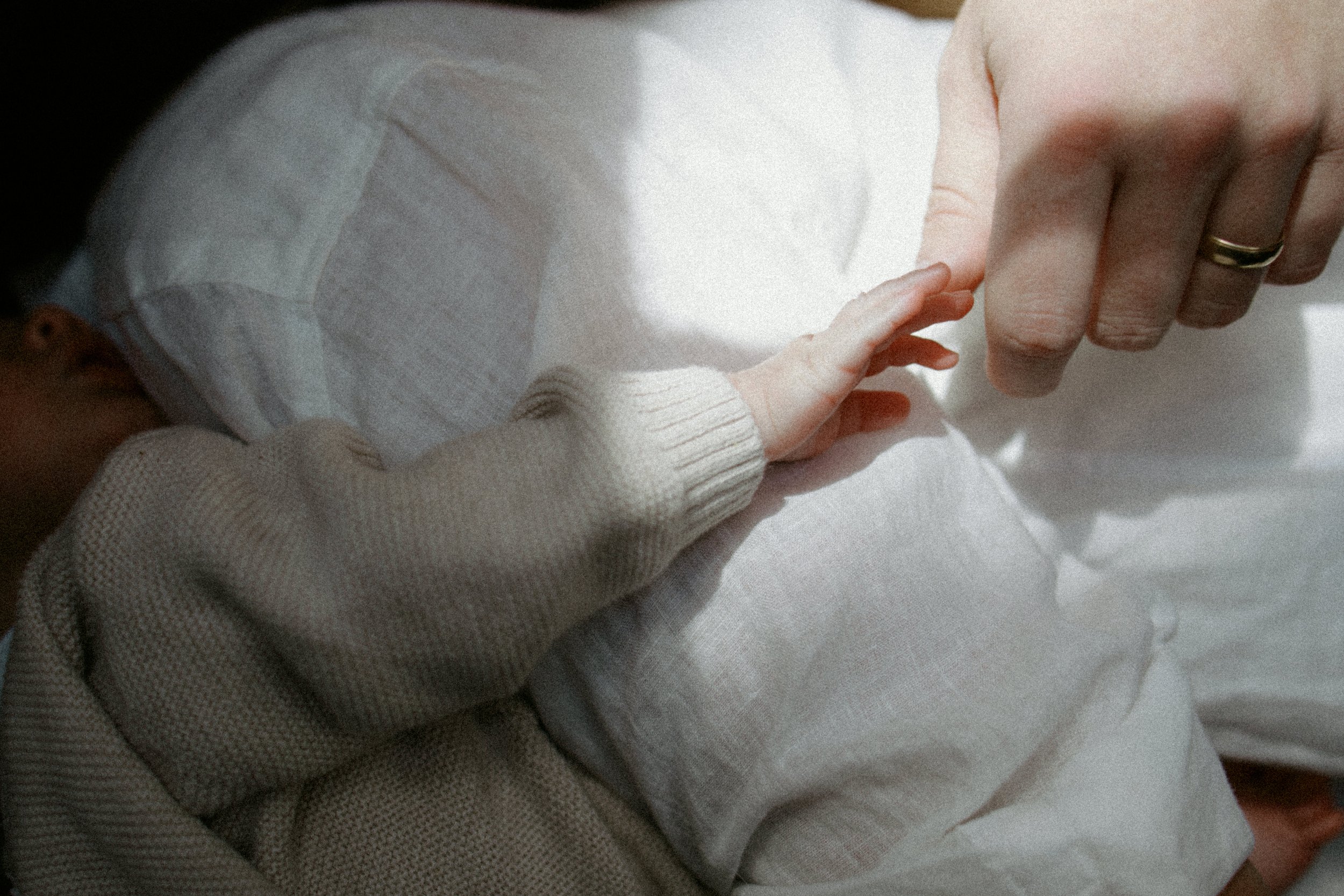 Soft documentary newborn photography detail of a baby reaching for a parent’s hand during an intimate in-home session in McHenry County, Illinois.