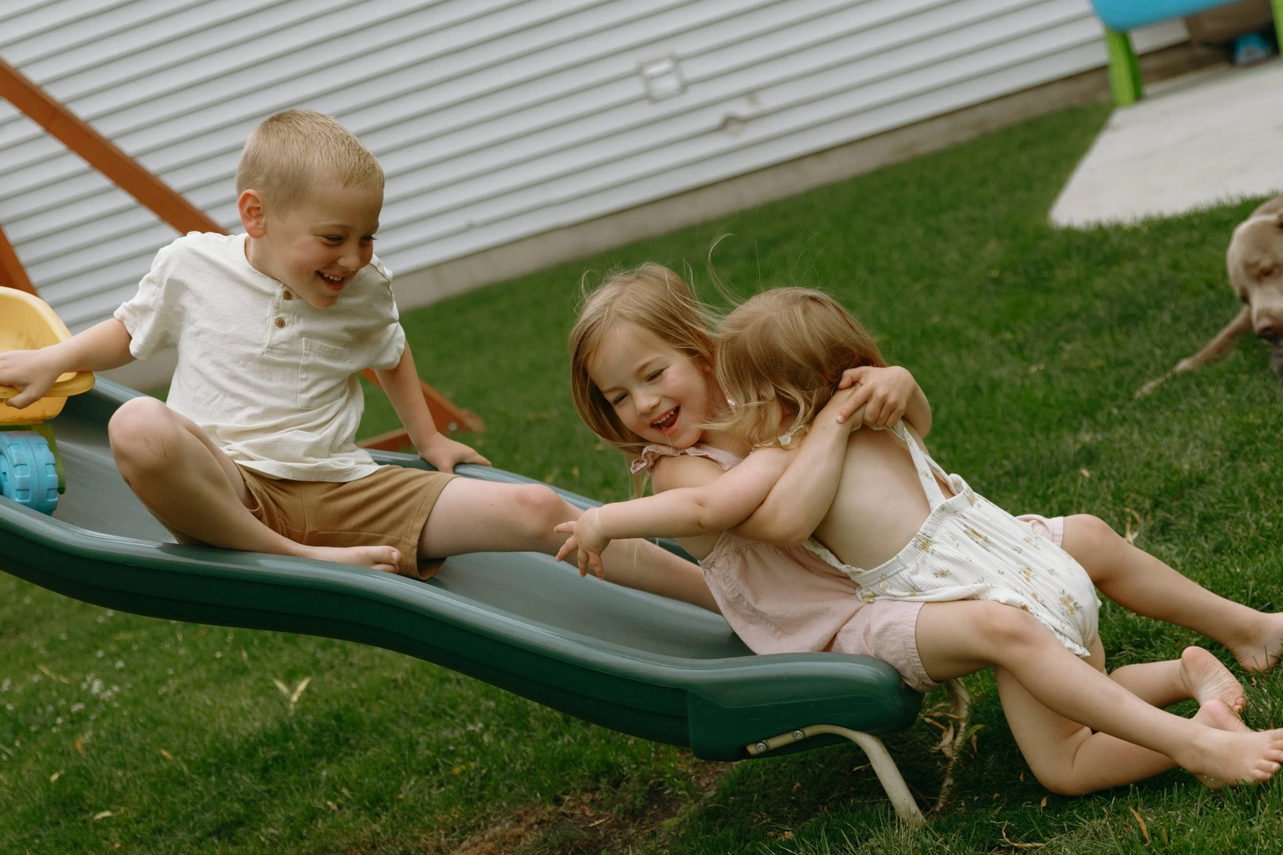 Documentary family photography of siblings playing on backyard slide in McHenry County Illinois, Nicole Kilday Photography