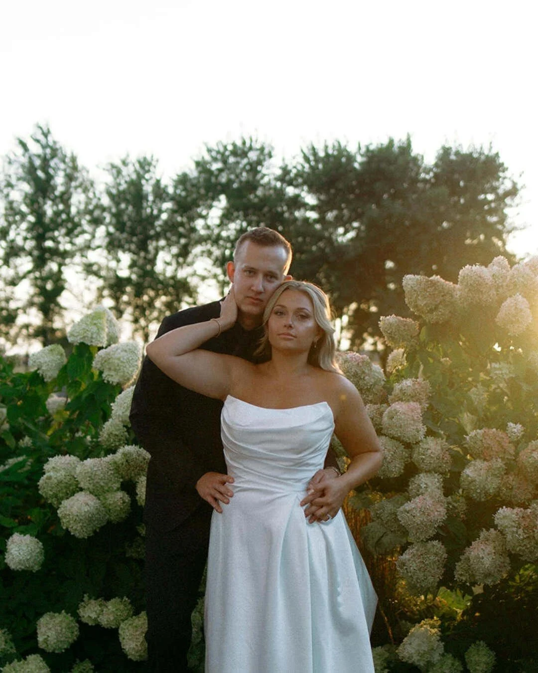 Bride and groom posed among white hydrangeas in golden hour backlight — Illinois and Wisconsin wedding photographer Nicole Kilday at Bluestem Farm and Events, Illinois