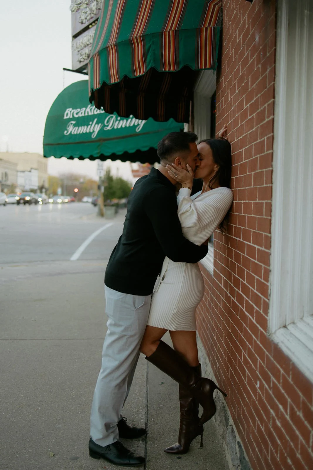 Faith and Luis sharing a kiss on a downtown sidewalk during their engagement session in Lake Geneva, Wisconsin.