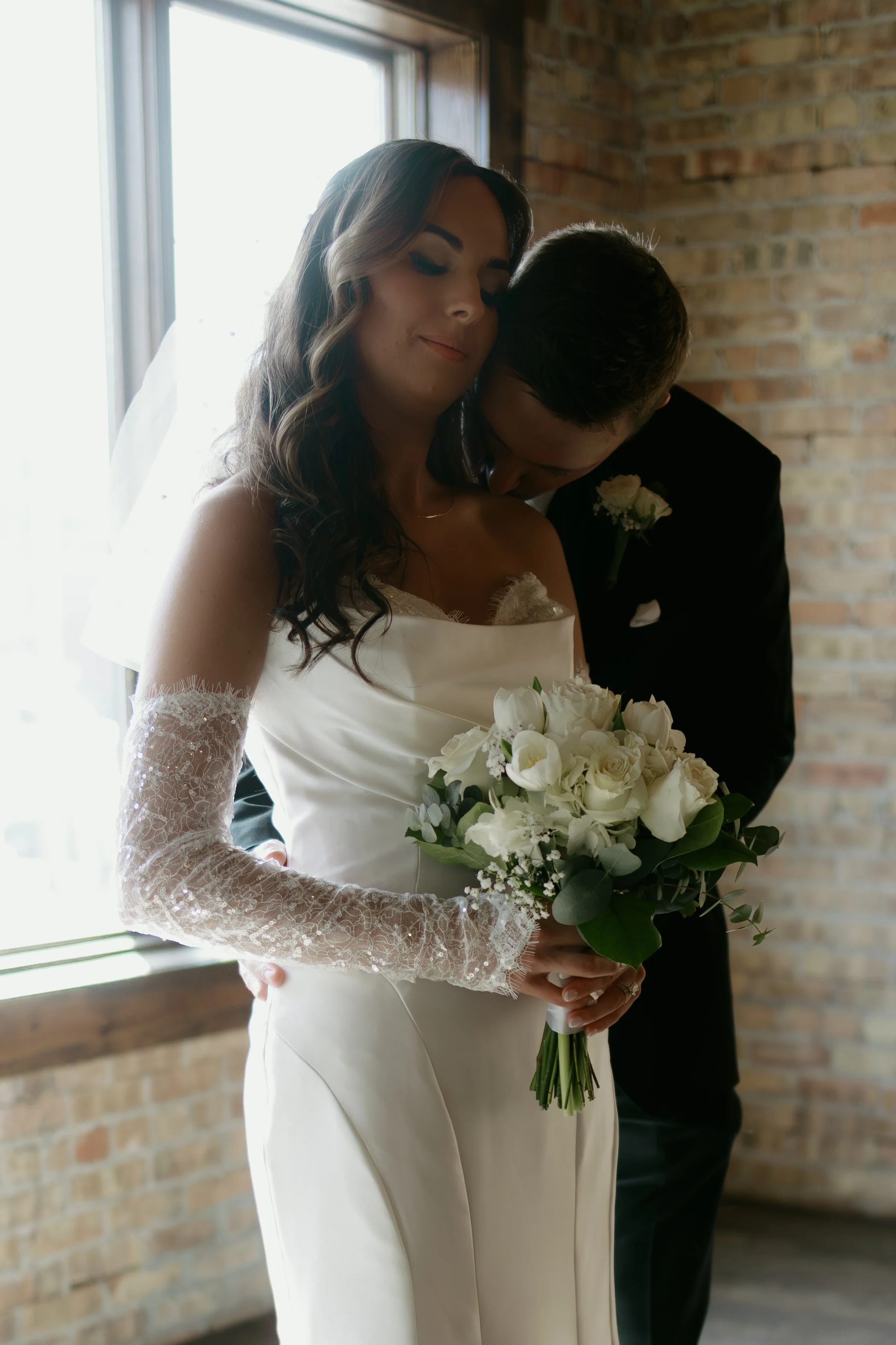 groom kissing his brides shoulder while she nuzzles in after their wedding ceremony at Ethereal Events in Woodstock, IL