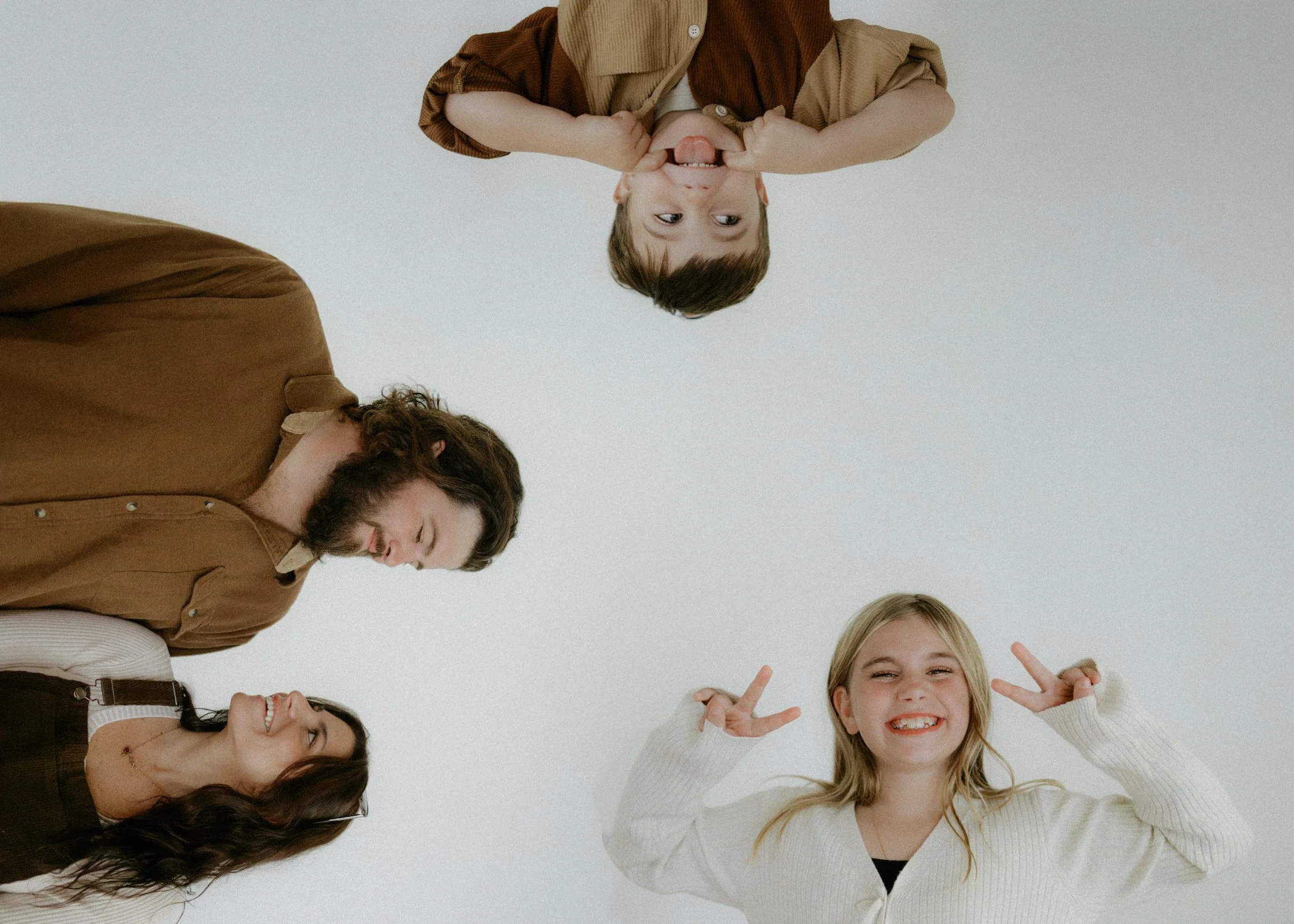 Four people, two men and two women, are looking overhead and smiling, with a plain white background.