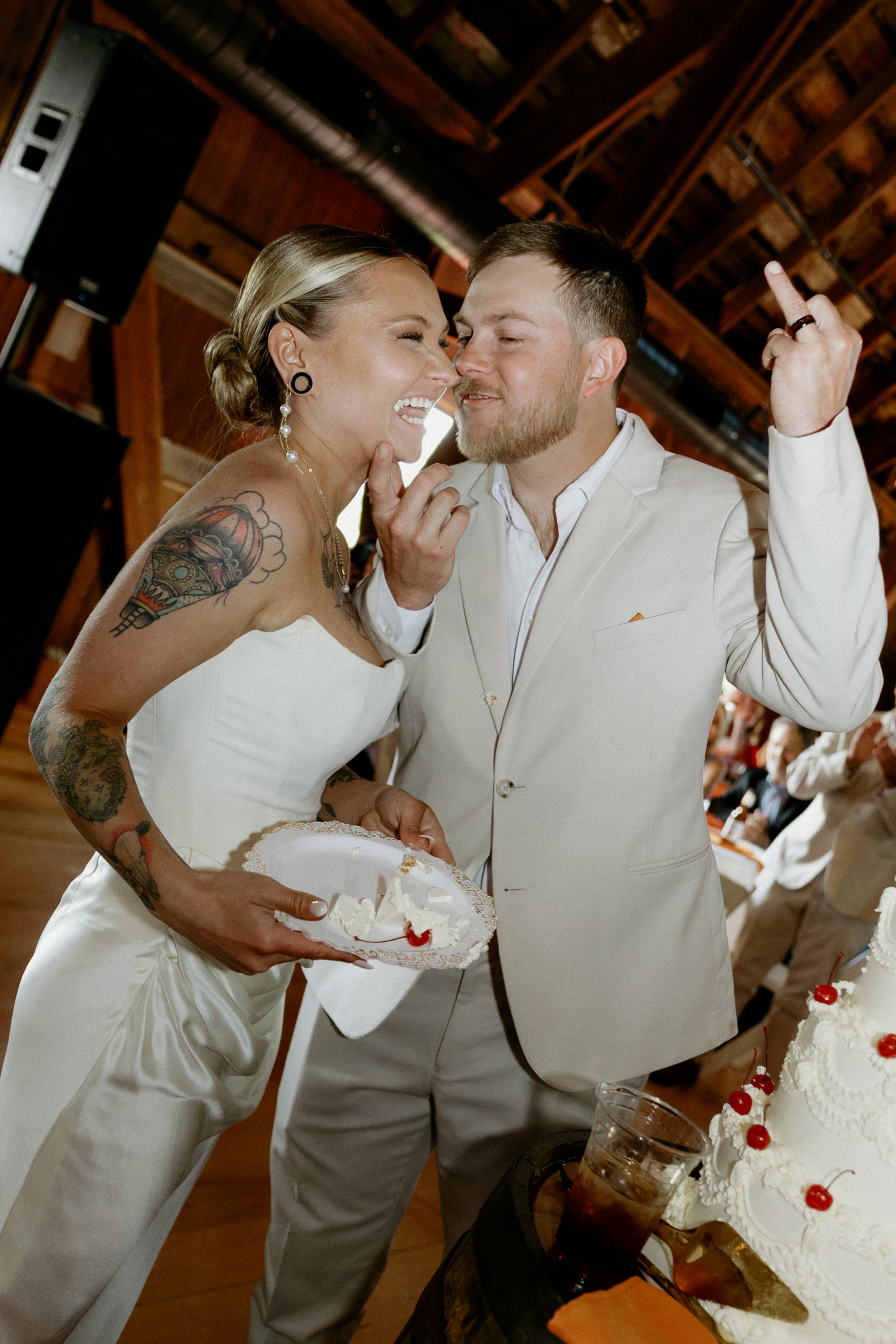 Bride and groom laughing during cake cutting at a barn wedding reception photographed by McHenry County Illinois wedding photographer Nicole Kilday