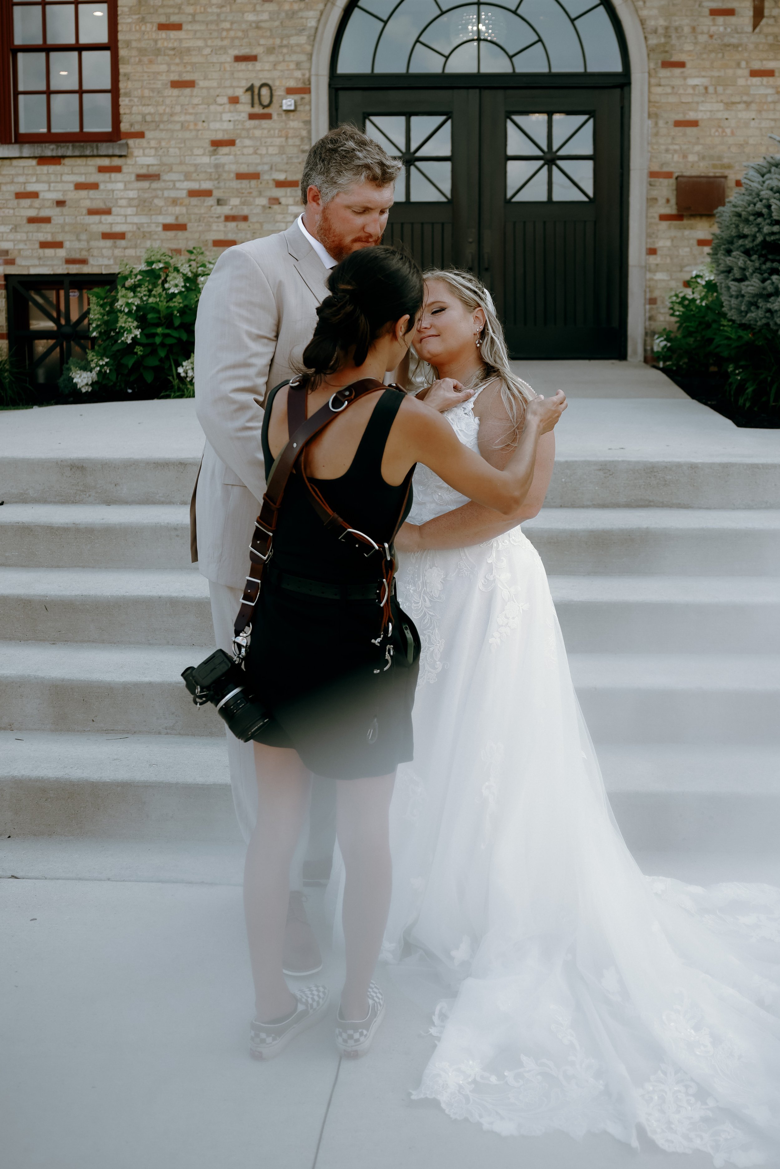 Wedding photographer adjusting a bride’s hair and dress before portraits begin at a Southern Wisconsin wedding.