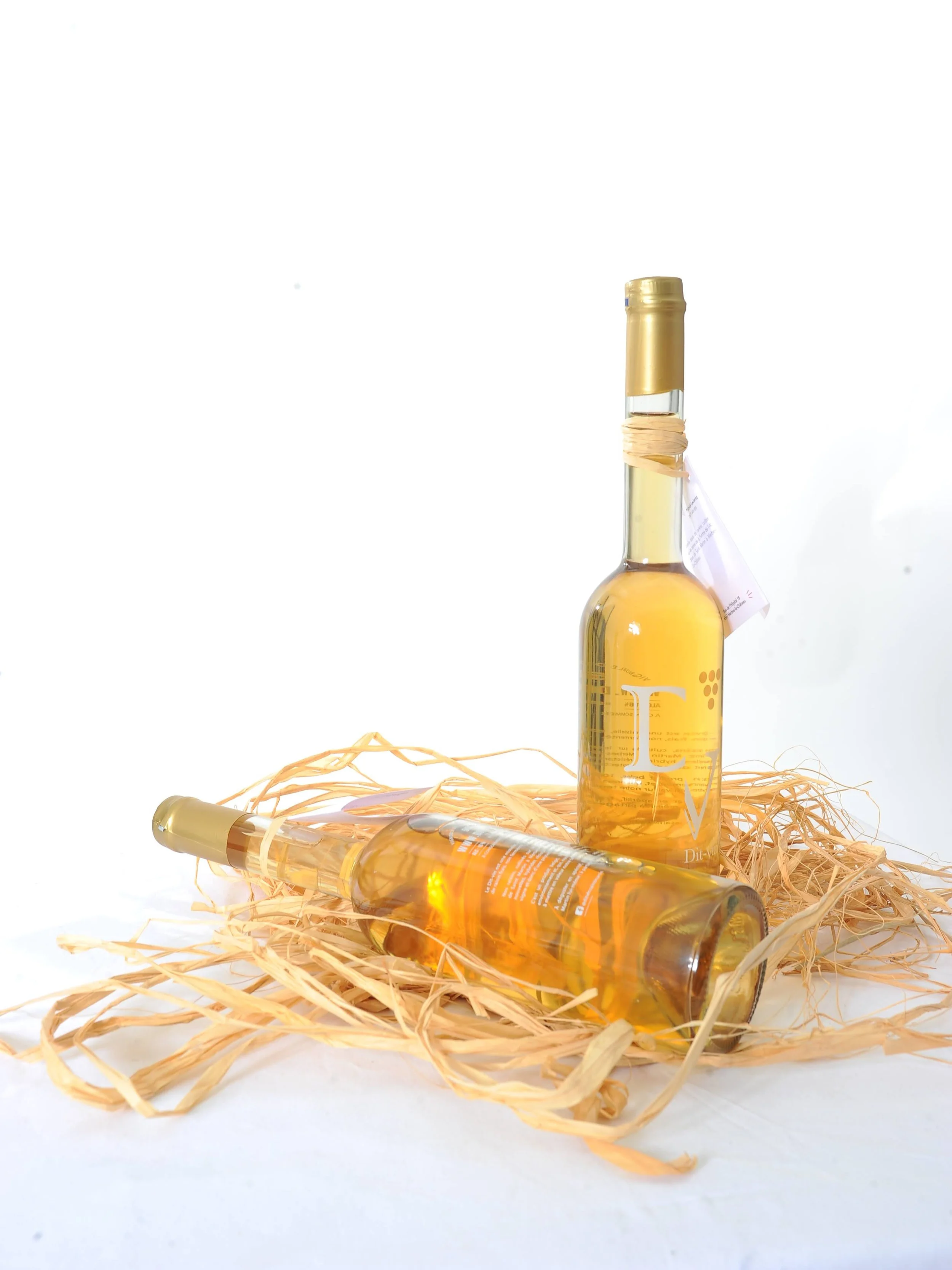 Bouteille de vin blanc posée sur une couche de paille de décoration.