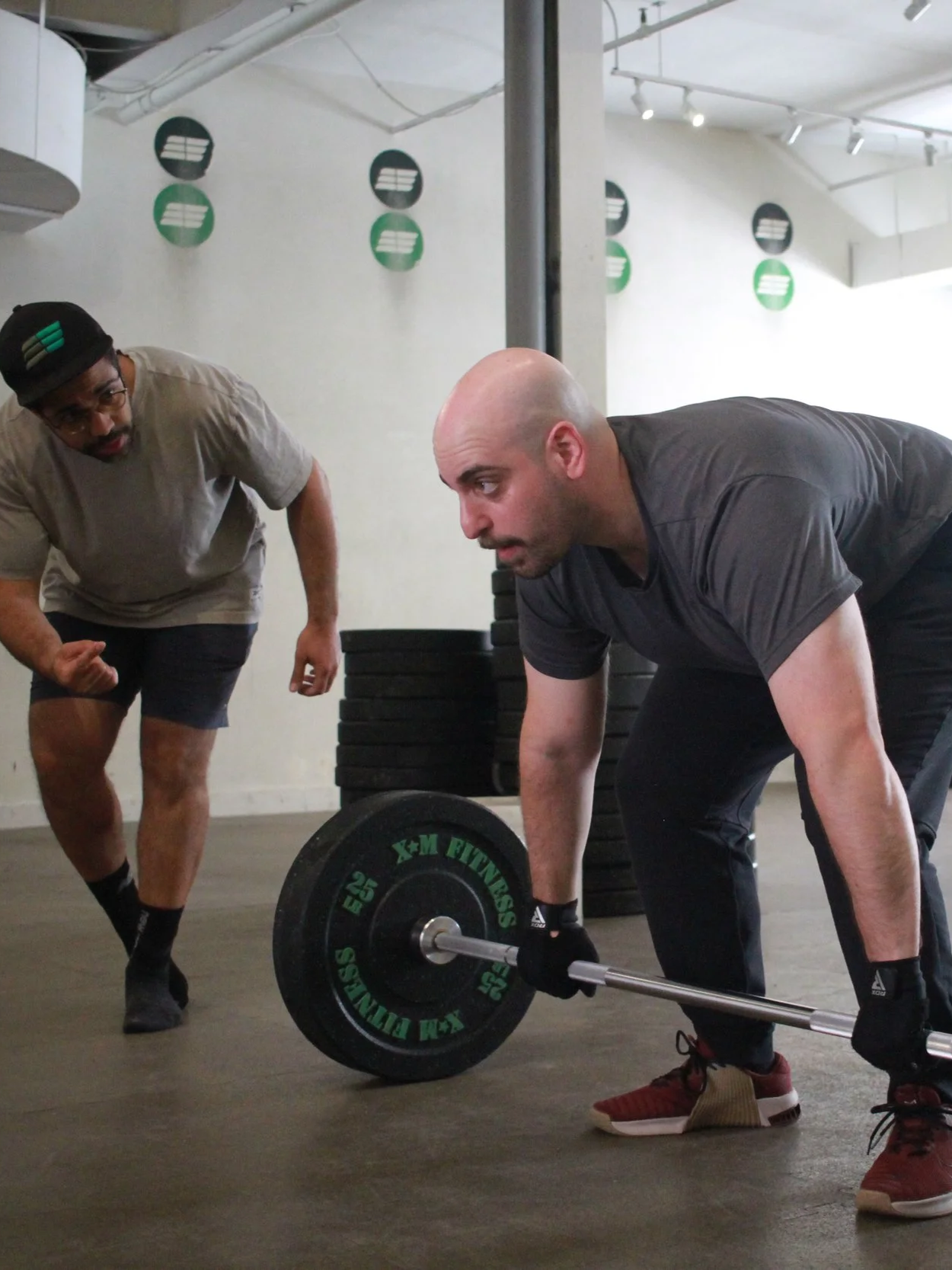 Empact Athletics coach guiding a member through a lift during a one-on-one coaching session in Toronto