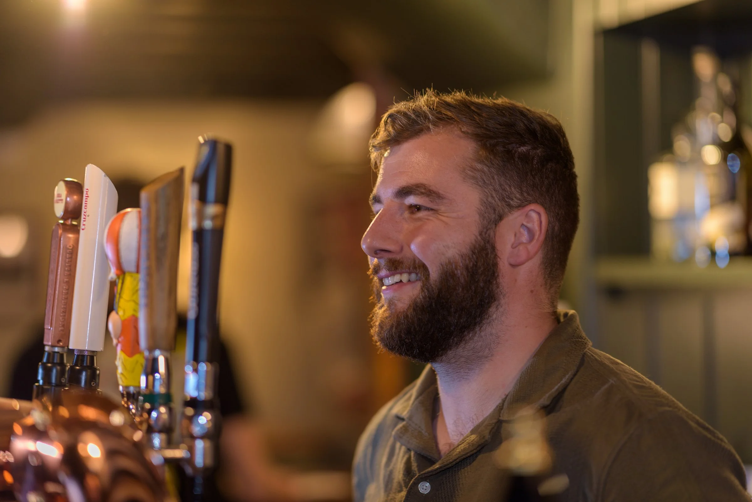 Seasonal dishes and drinks enjoyed with friendly pub service, bartender smiling beside the bar taps
