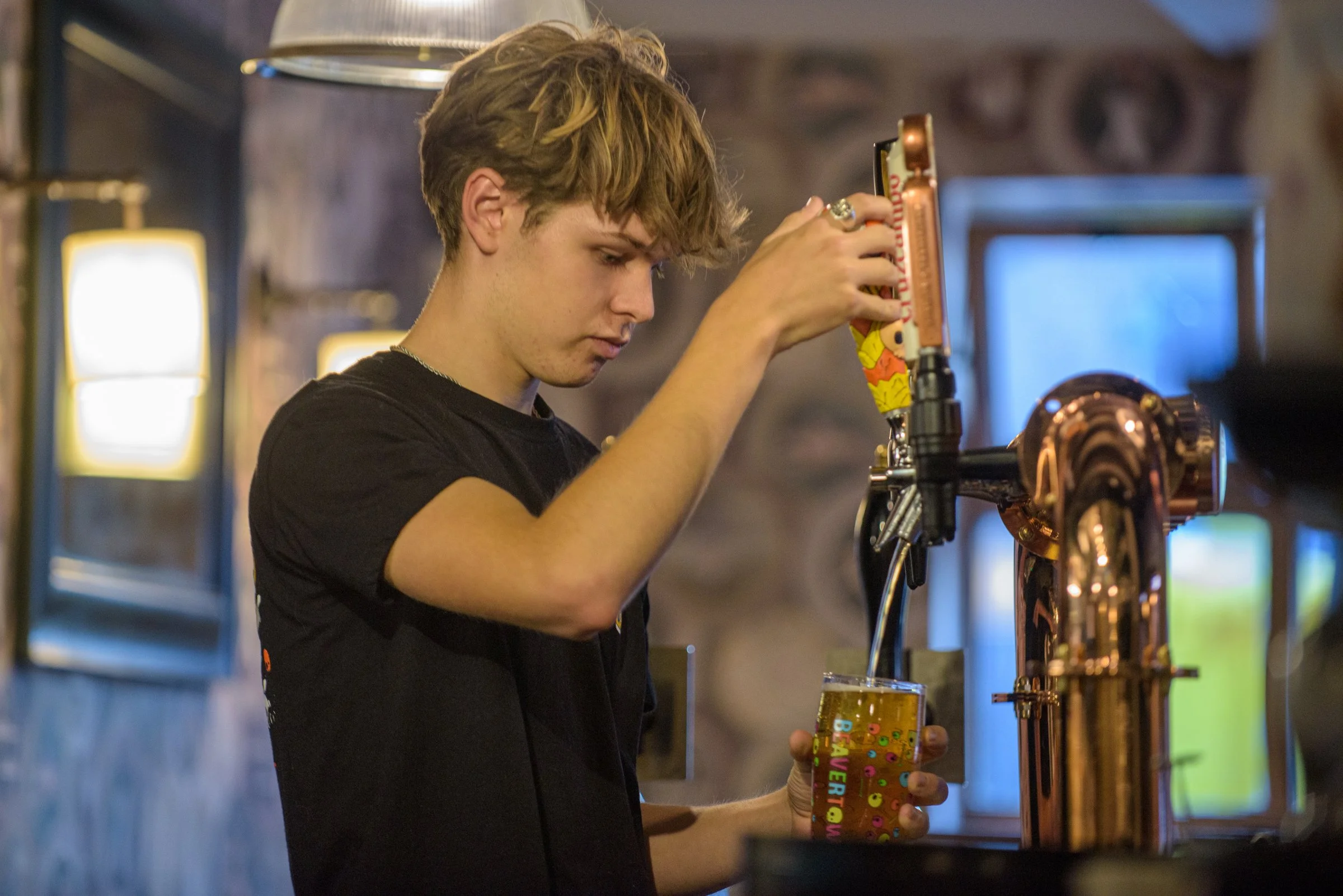 A bartender pouring a pint of beer on tap, preparing drinks to accompany seasonal dishes