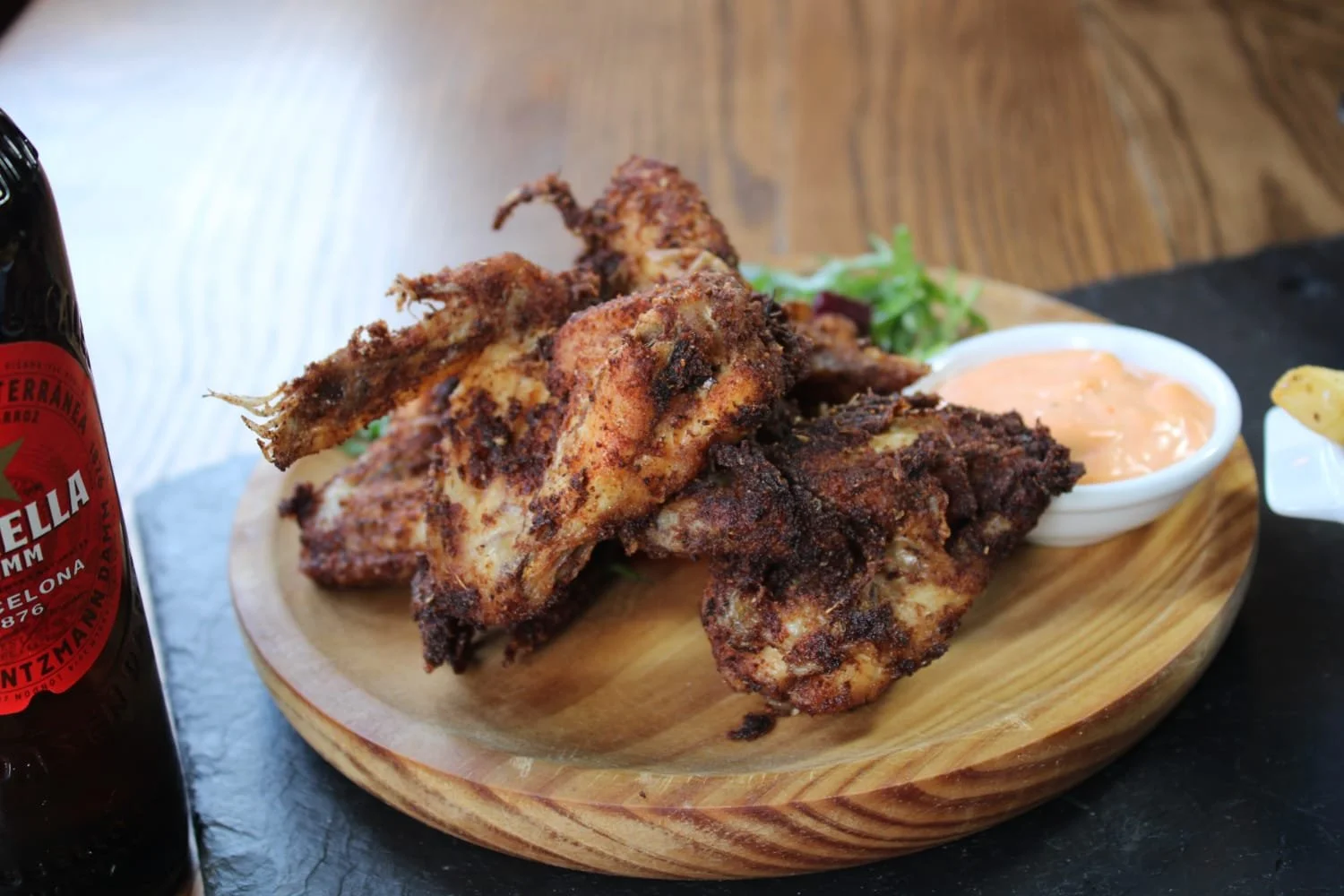 Seasonal dishes including spiced grilled chicken wings with dipping sauce, served with beer.