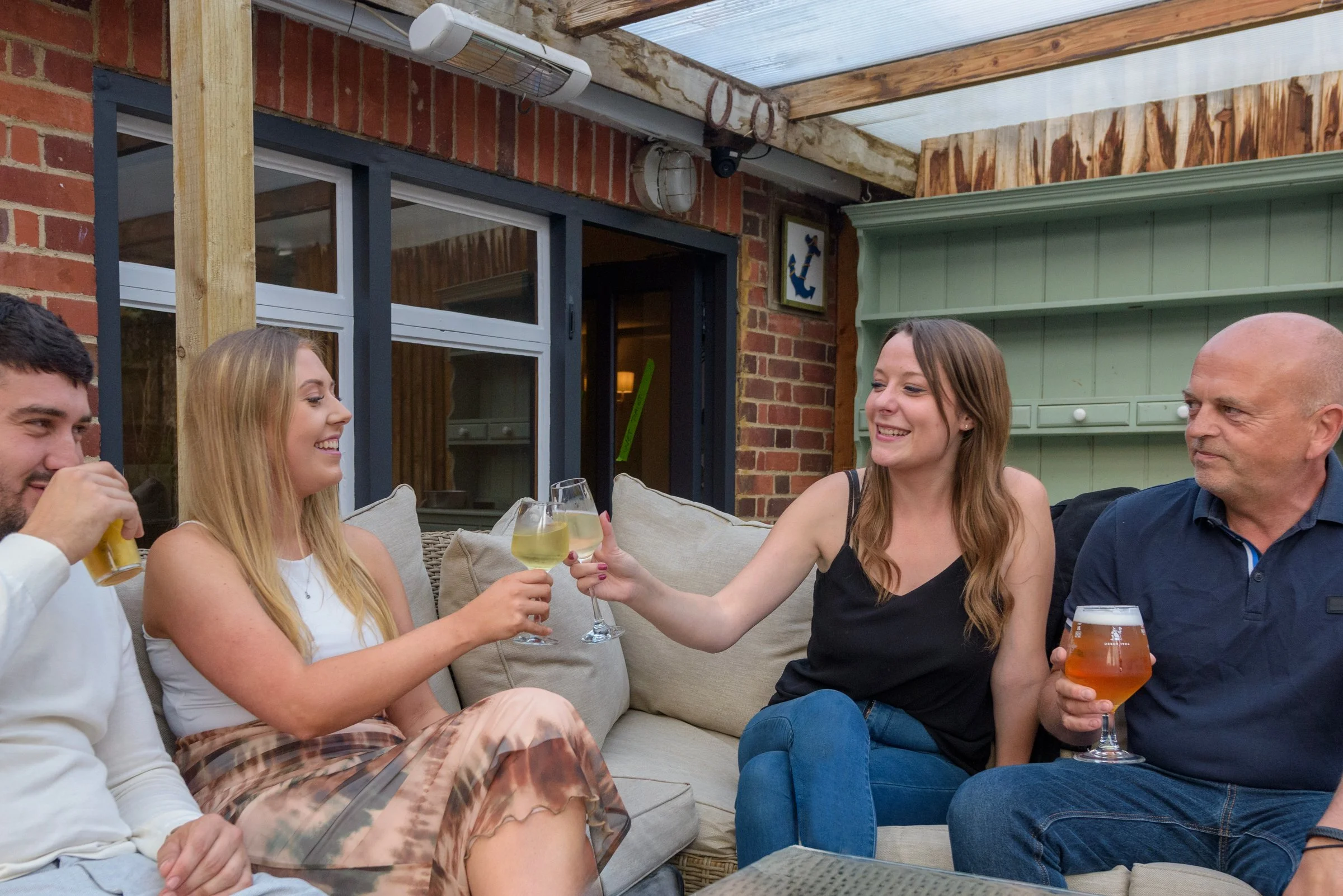 Friends raising their glasses in a toast on the pub terrace, celebrating with drinks and seasonal dishes