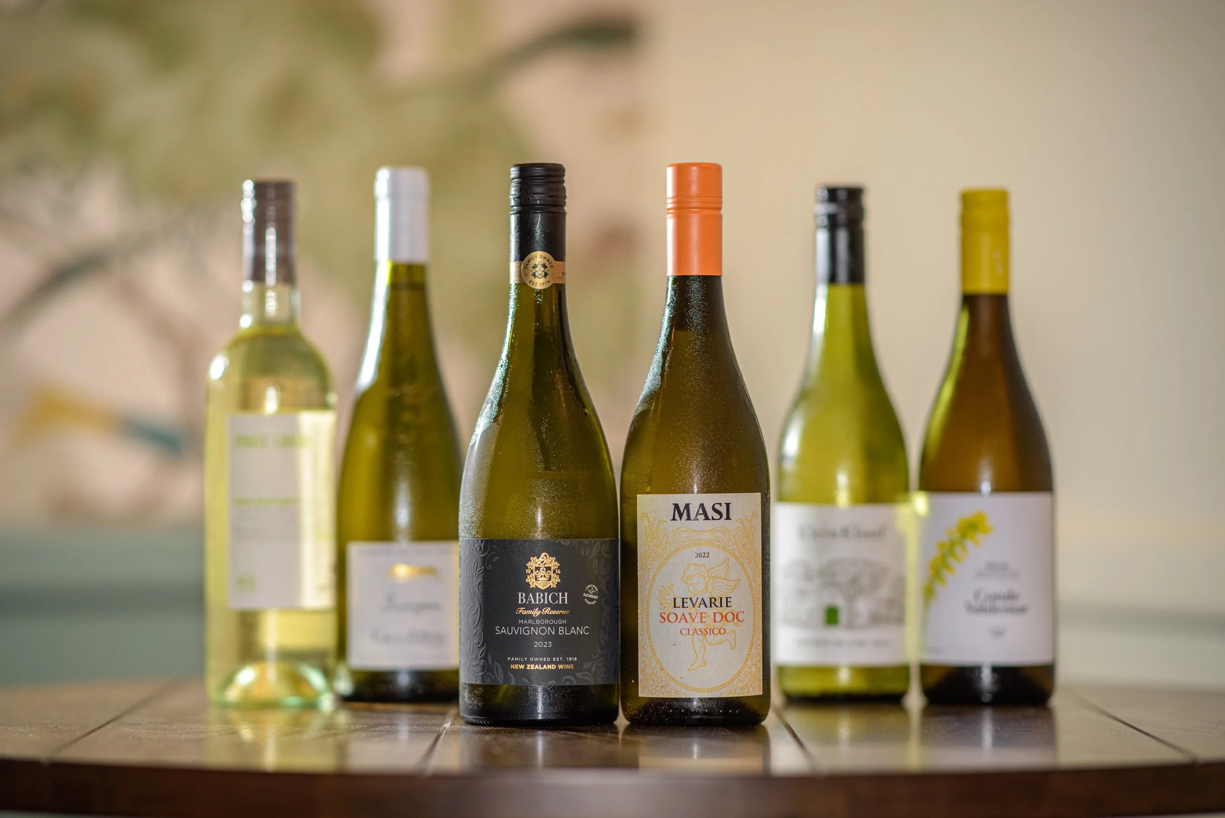 A collection of chilled white wine bottles arranged on a wooden table, ideal for enjoying with seasonal dishes