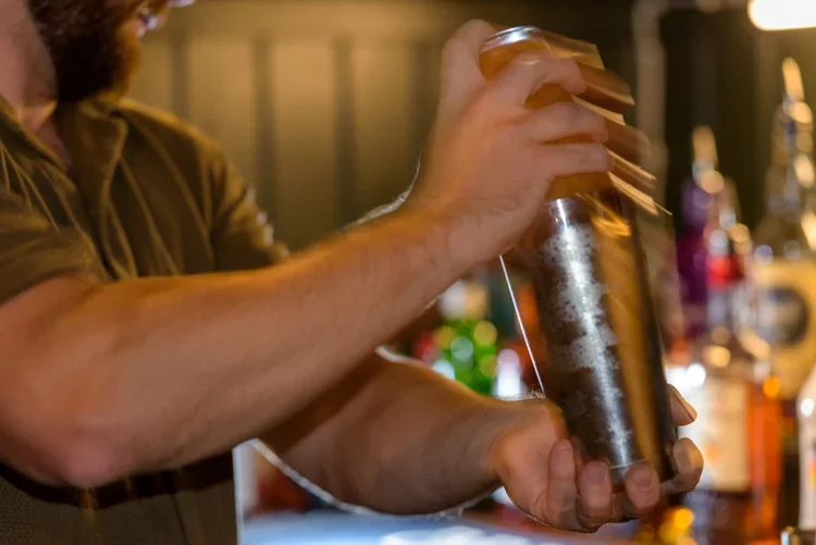 Bartender preparing a cocktail in a lively casual dining bar atmosphere