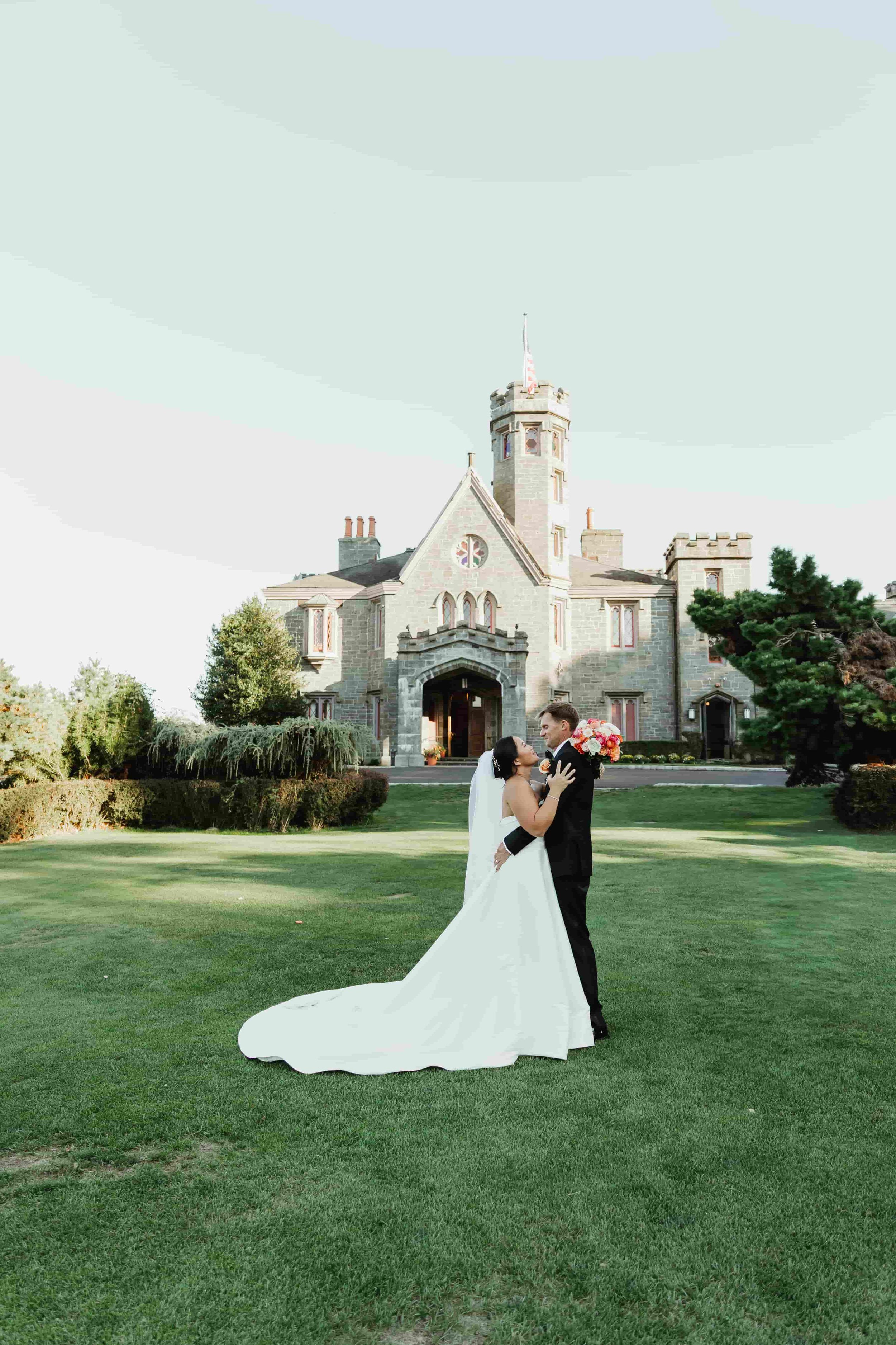 Bride and groom sharing a romantic moment in front of a castle-like building on their wedding day in connecticut