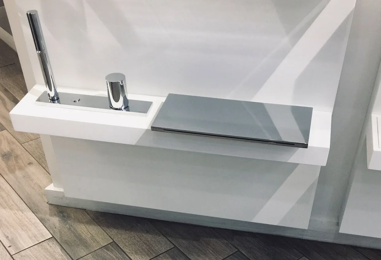 A desk with a built-in sink, a chrome faucet, a soap dispenser, and a closed laptop.