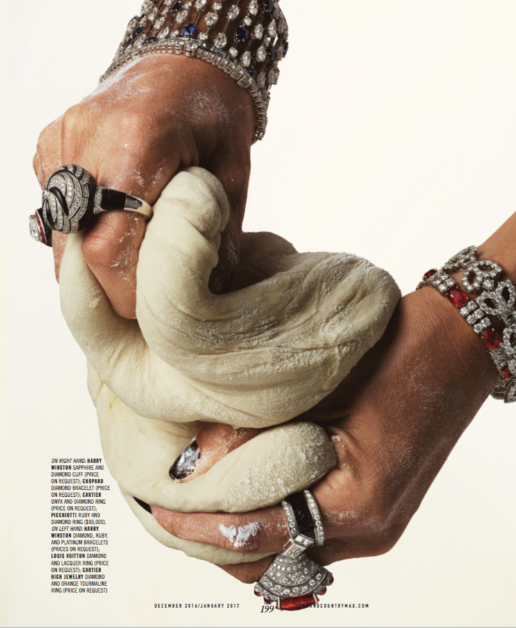 Close-up of hands with multiple rings, bracelets, and jewelry forming a fist, with a ball of dough in the grasp.