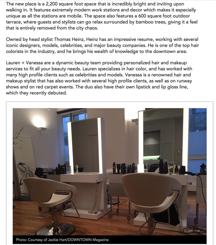 Modern hair salon with two illuminated mirrors, styling chairs, and various hair products on counters, inside a bright, contemporary space.