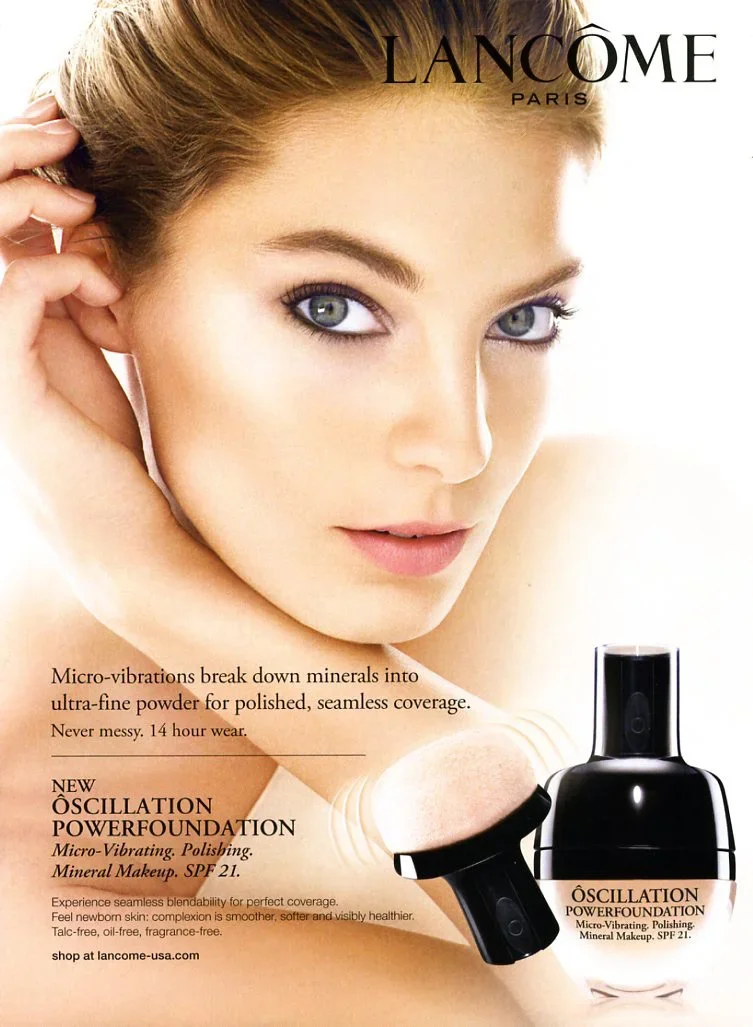 Front view of a woman with light skin and blue eyes showing her face and shoulder, touching her hair. The image features Lancôme Paris branding and an advertisement for Oscillation Powerfoundation, a micro-vibrating liquid foundation with SPF 21, wit
