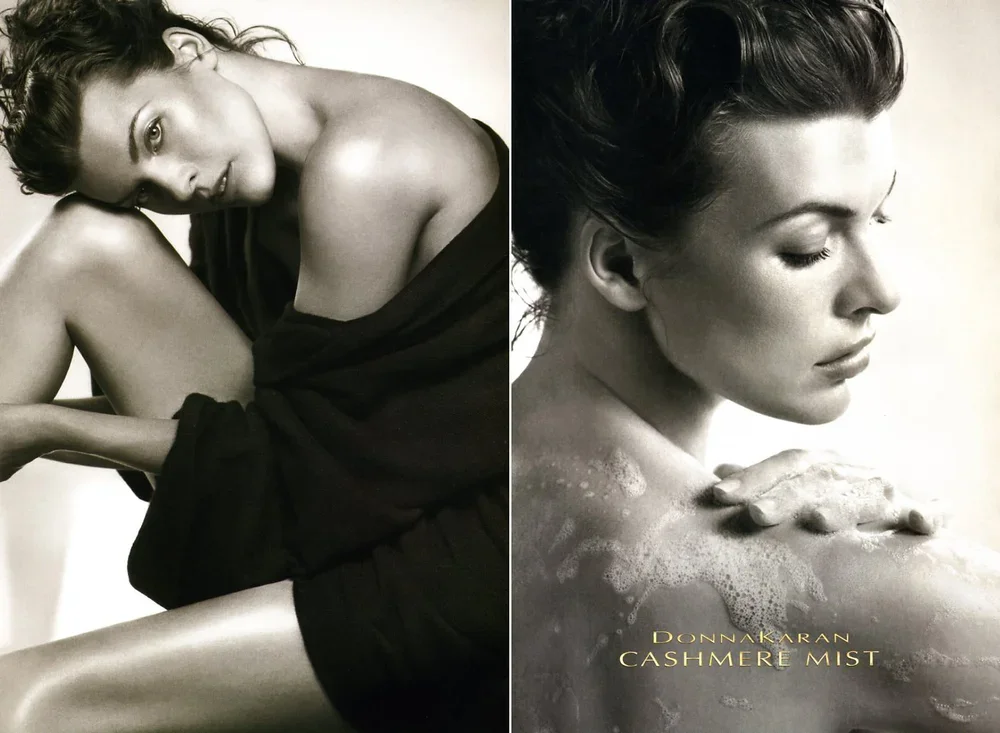 Black and white advertisement featuring a woman with short dark hair, sitting with her knees drawn up and her arms wrapped around her legs, wearing a loose black garment; another woman with short dark hair, shown in profile, appears to be applying cr