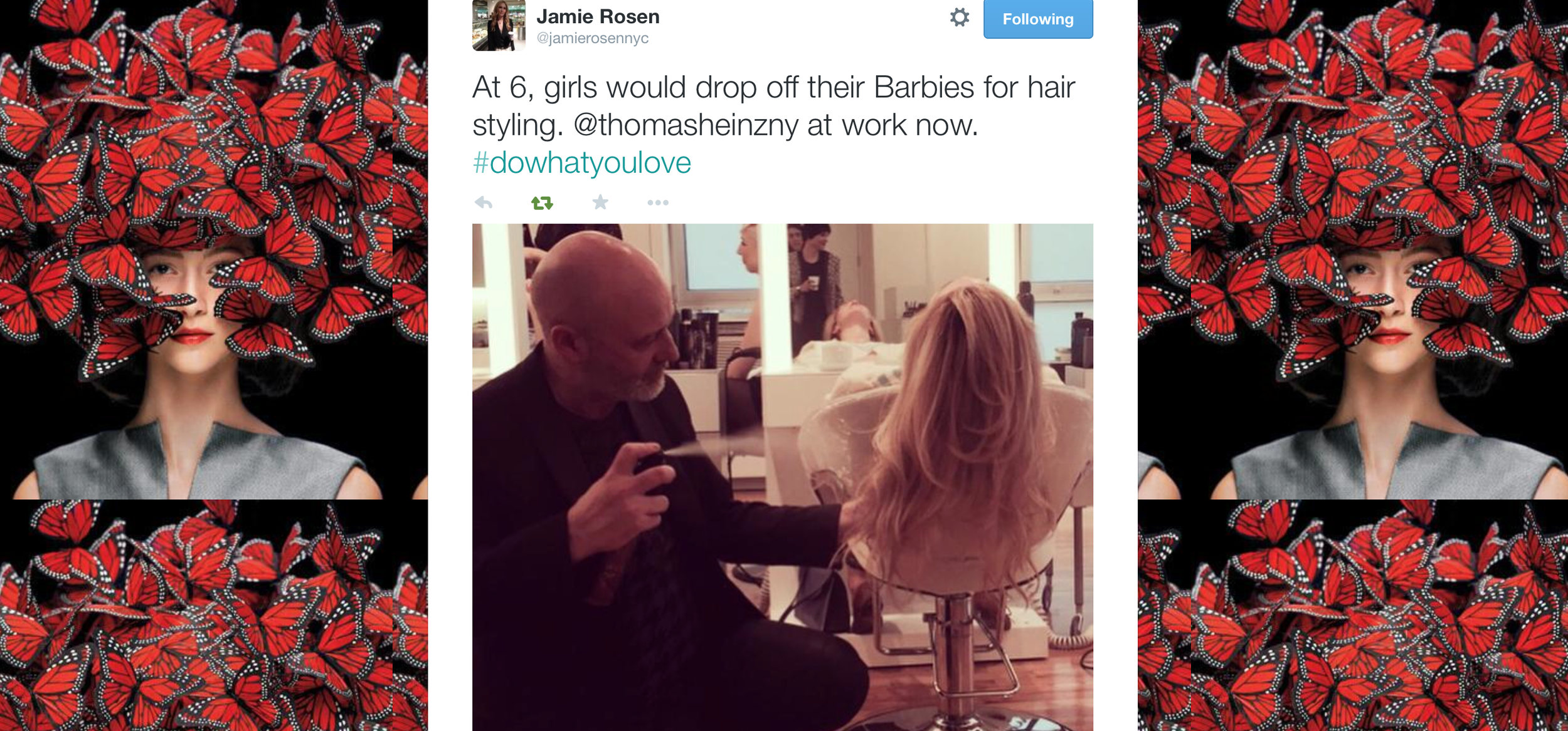 A woman with long, wavy red hair lying back in a salon chair, receiving a hair treatment, while a stylist in a black jacket with a white shirt underneath, appears to be working on her hair, in a bright salon with large windows in the background.