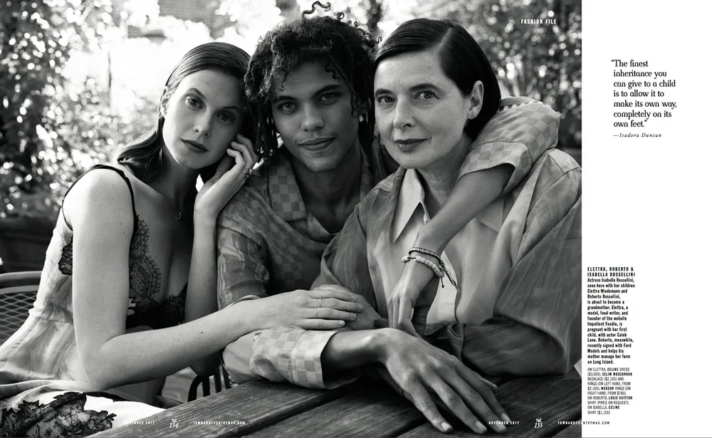 A black and white photo of three people sitting closely together outdoors, a young woman on the left, a young man in the middle, and an older woman on the right, with the young woman and older woman touching each other and smiling.