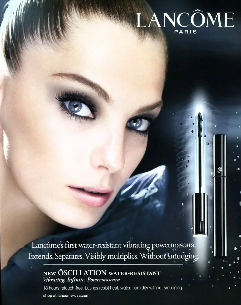 Close-up of a woman with blue eyes and makeup, advertising Lancôme's water-resistant vibrating power mascara with one mascara tube shown.