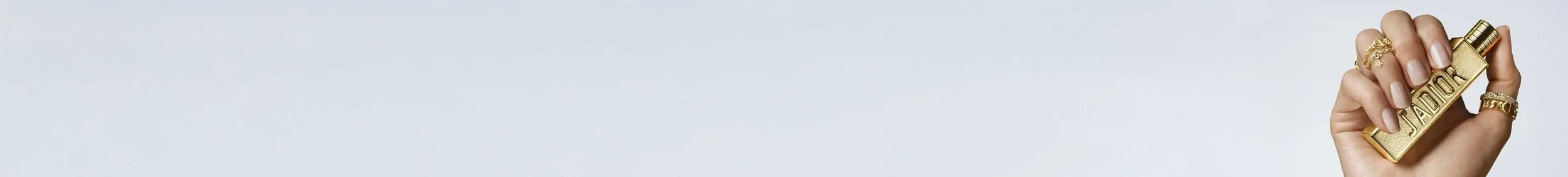 Hand holding a gold lighter with the word 'STARDOM' engraved on it, wearing multiple rings and light-colored nail polish.