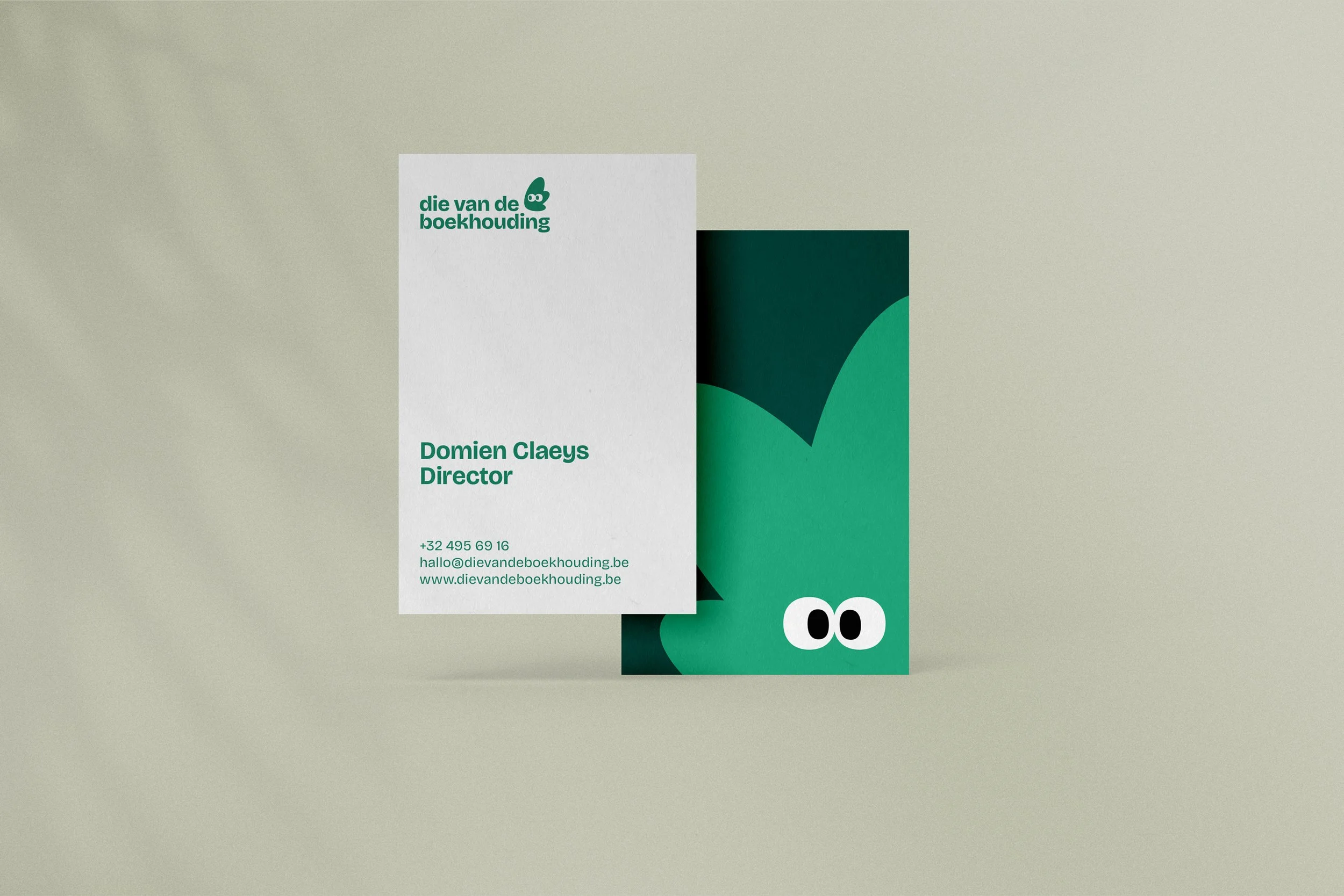 Business card with a cartoon crocodile face illustration on a green background, featuring two eyes with black pupils and white sclera. The card includes contact information and a logo with stylized green leaves and the text 'die van de boekhouding' in green.