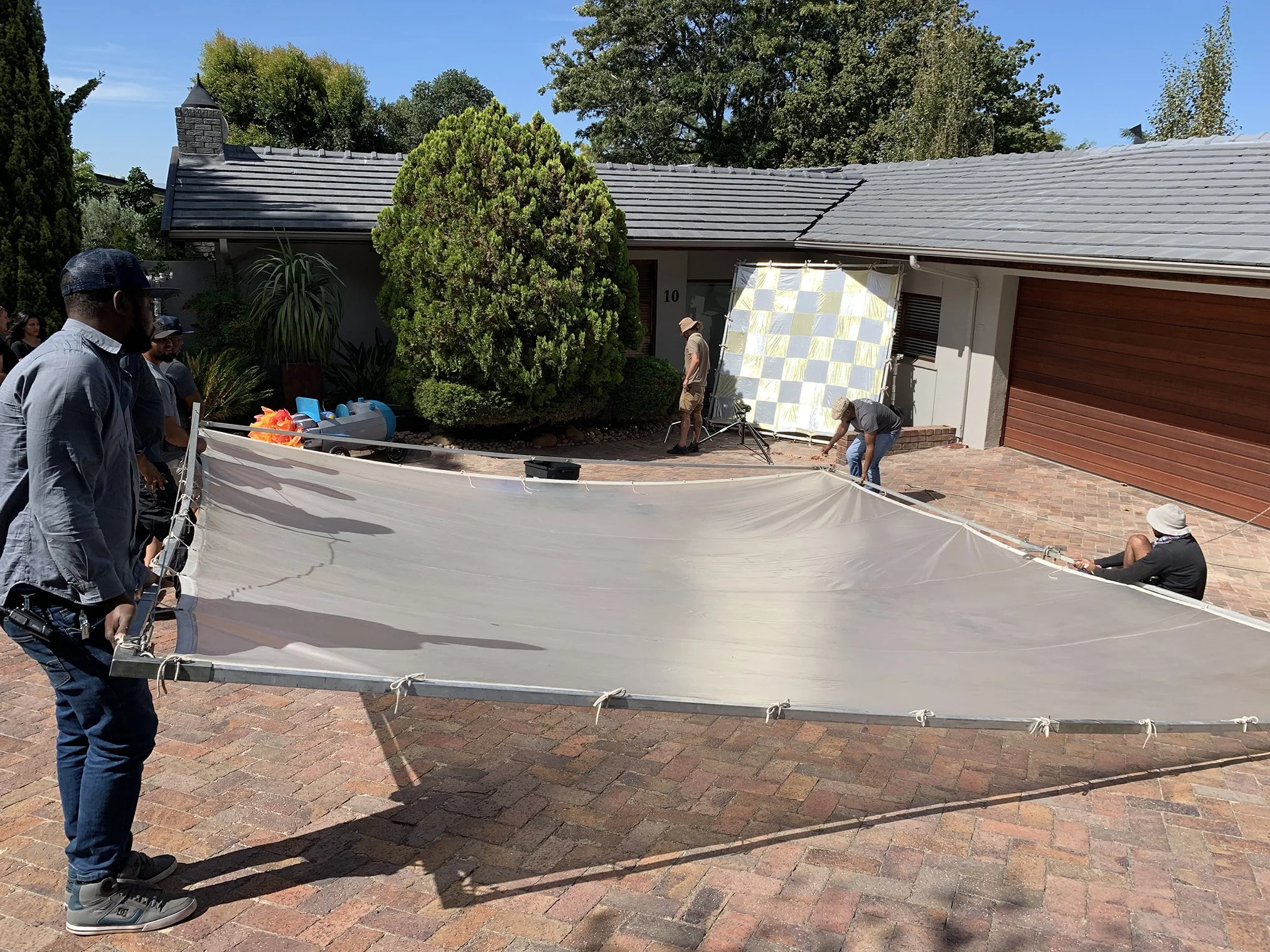 People working together to set up or take down a large outdoor screen in a driveway.