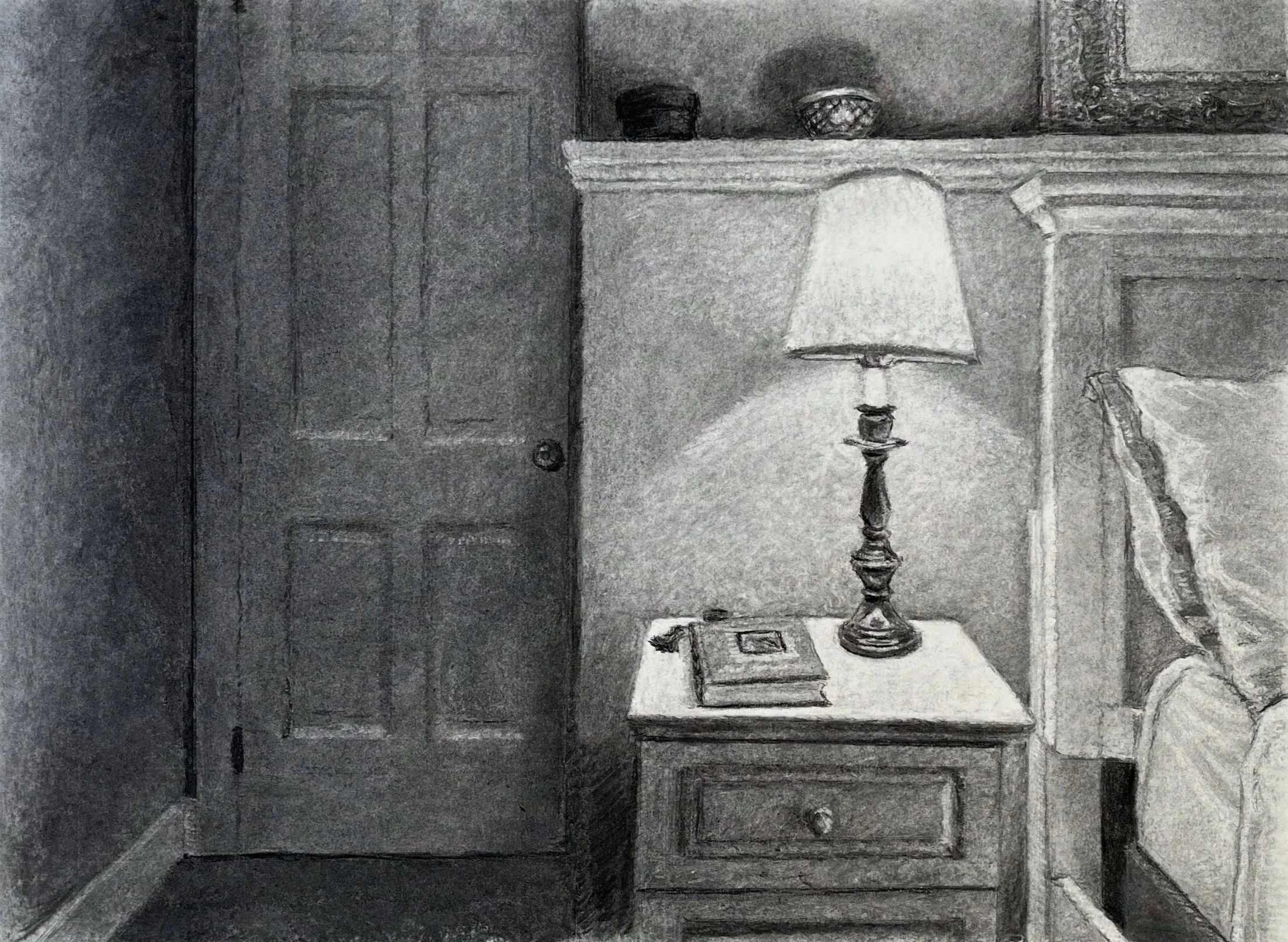 A bedroom with a nightstand, lamp, and book.