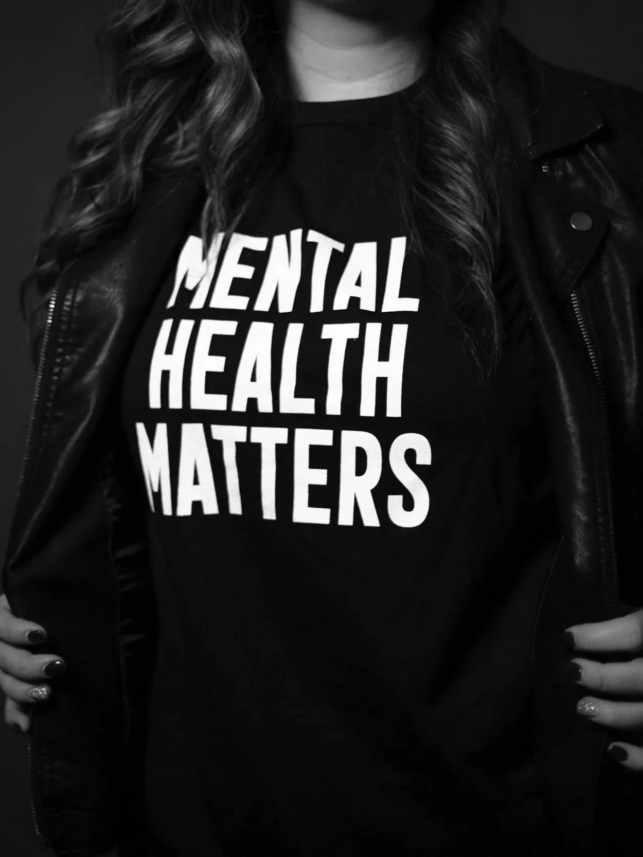Person wearing a black T-shirt with the text 'Mental Health Matters' and a black leather jacket.