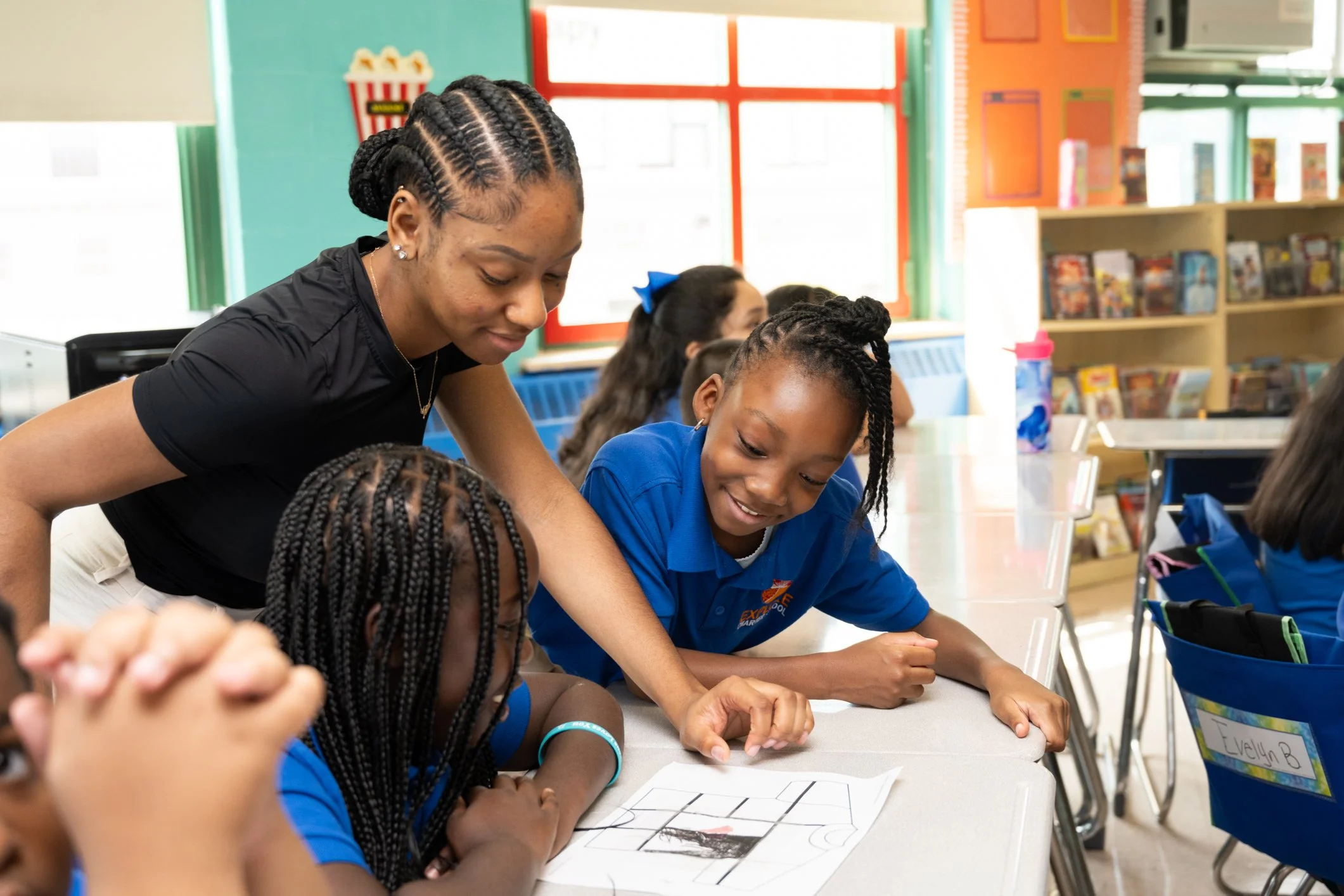 Teacher helping students with a drawing activity in a classroom.