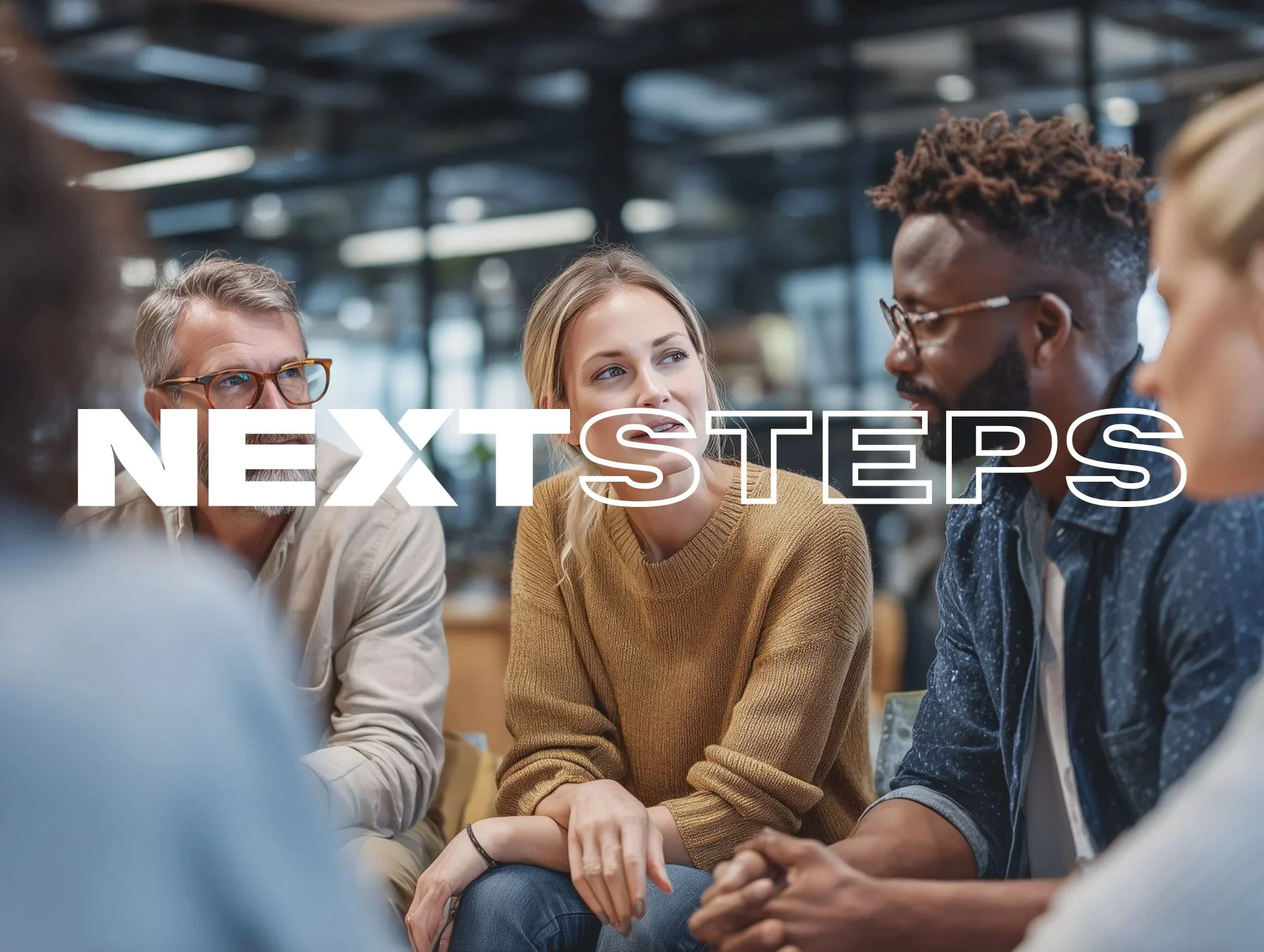 A diverse group of five people sitting together in a modern, well-lit indoor space, engaged in a discussion. The text 'NEXT STEPS' is overlaid on the image.