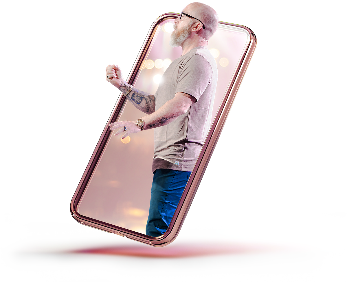 A man with a beard and tattoos on his arms is standing inside a large smartphone with a glowing, blurred background, giving the appearance he is emerging from the phone.