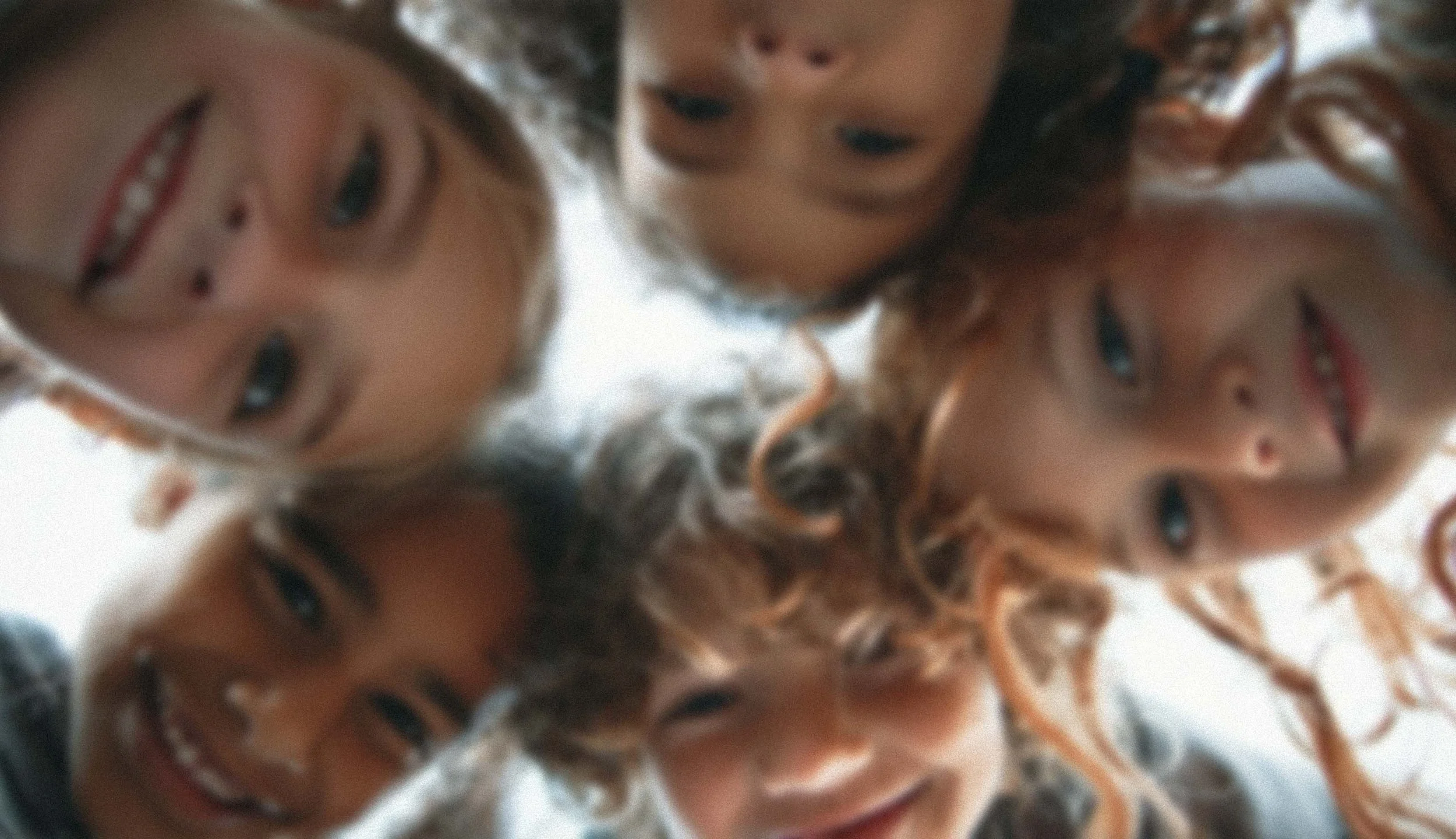 A group of children looking down at the camera in a circle, smiling and laughing.