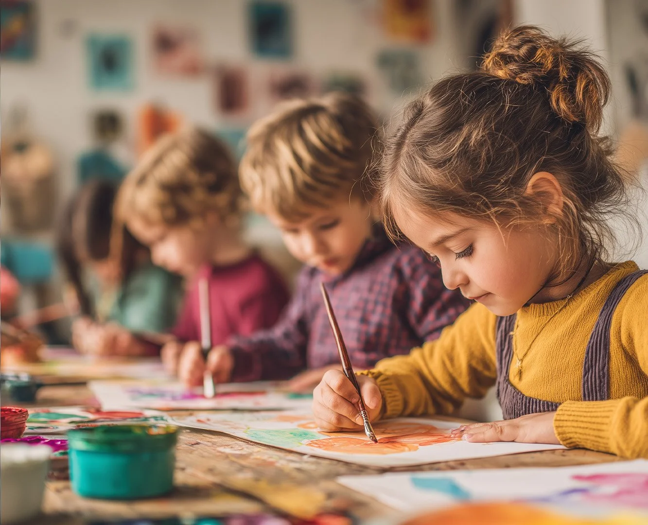 Children painting at a table in an art classroom, focused on their artwork.