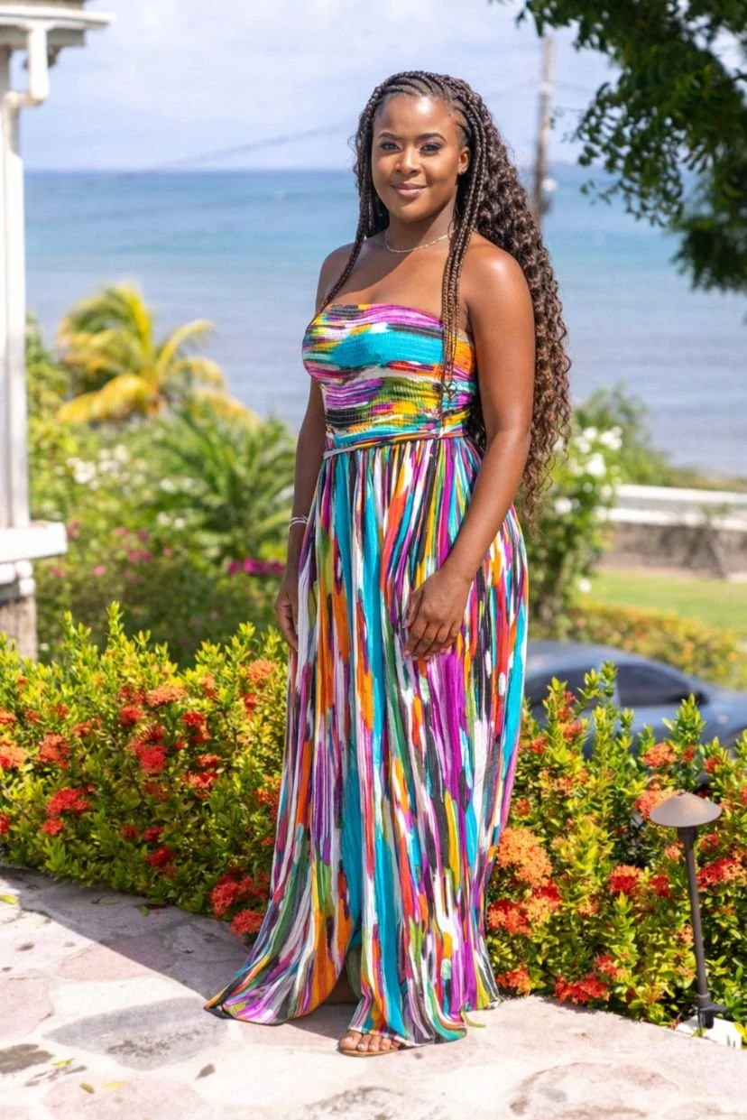 Charnette standing outside on a porch, smiling, with greenery and a house in the background.