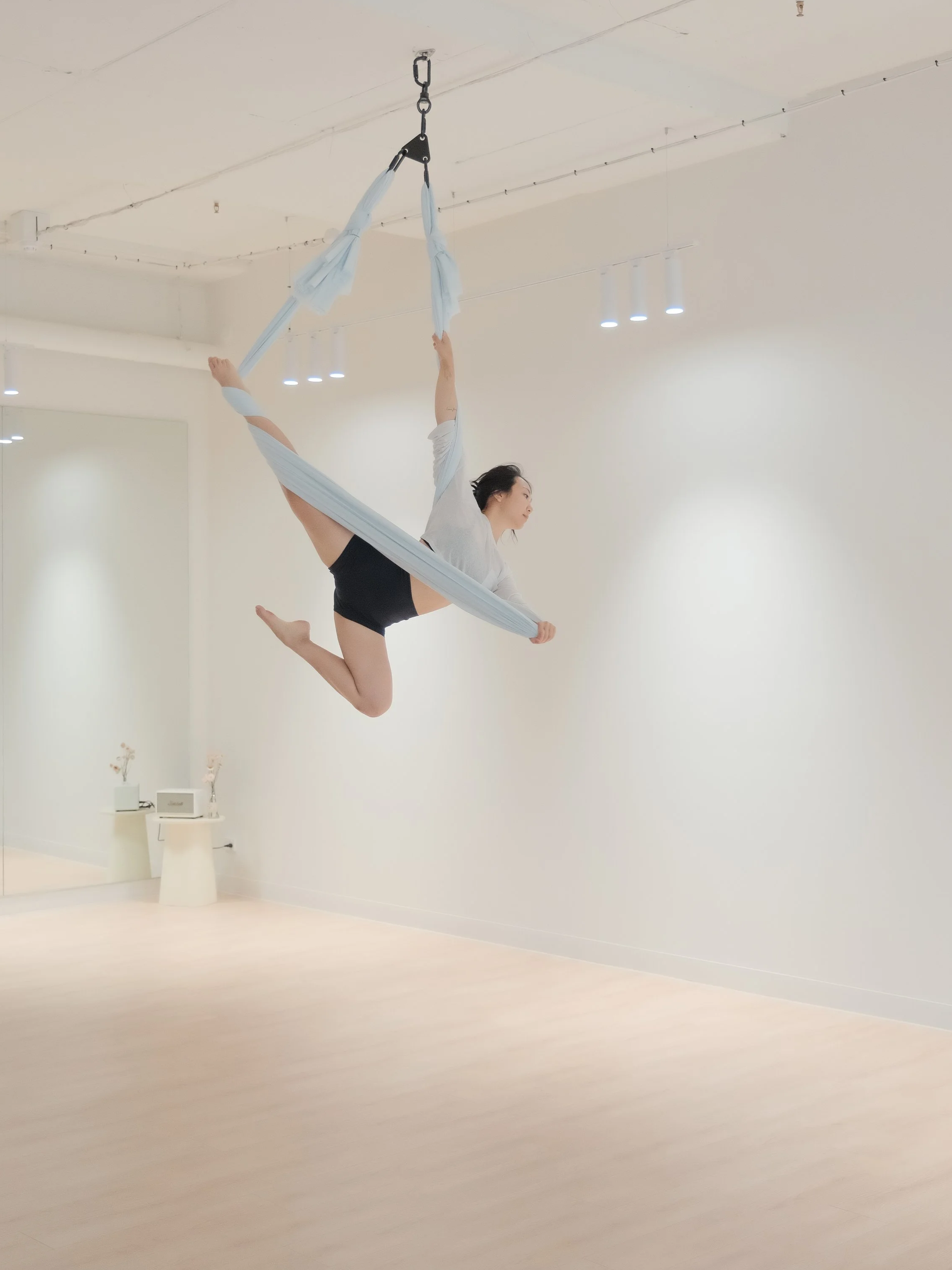 Minimal aerial studio in Melbourne CBD featuring hoop and hammock, with cozy tones and open space for flow practice.