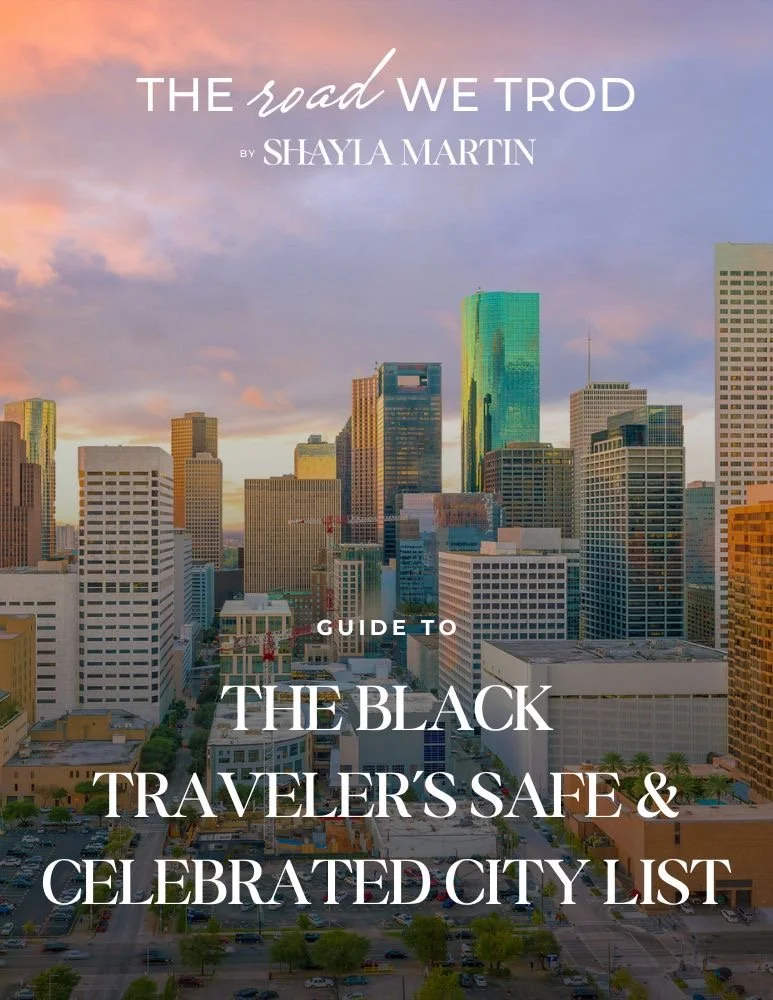 Cover of a guidebook titled 'The Road We Trod' by Shayla Martin, featuring a city skyline with skyscrapers at sunset.