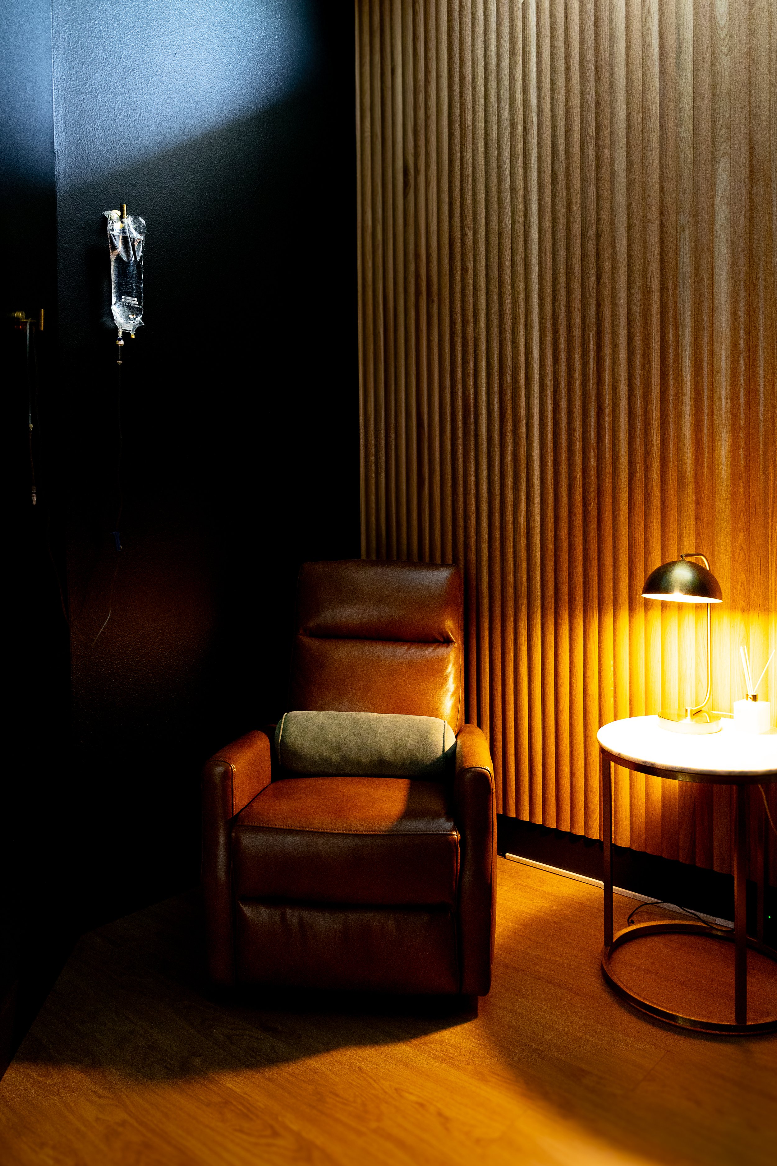 A single brown leather chair on a room with an IV bag hanging next to the chair